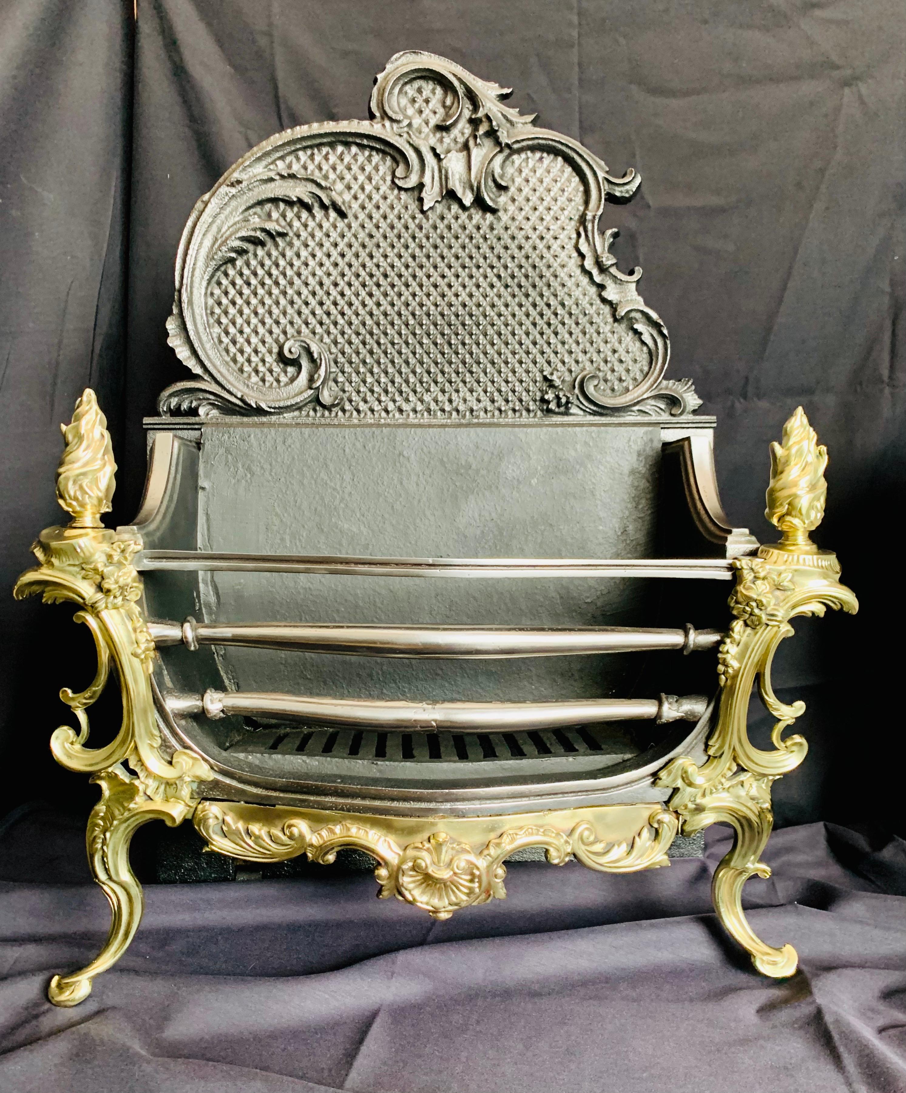 A very attractive 19th century Victorian French Rococo style brass and iron fire grate, with a polished three barred front above an ornate scrolled high arched backplate, twin flaming brass finials and a pair of elaborate scrolled legs linked by a