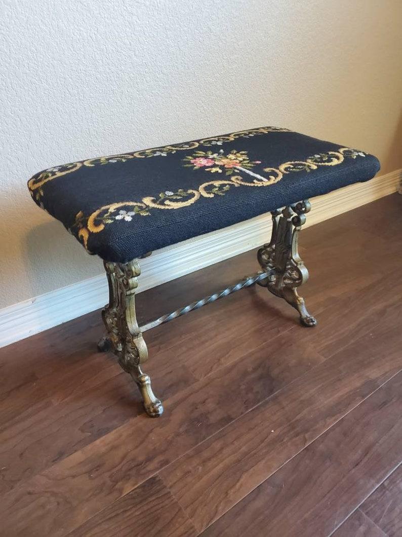 An exquisite Victorian period piano stool from the second half of the 19th century, having detailed needlepoint-covered seat with floral motif, over the ornate cast iron base with spiral turned stretcher, ending in paw feet, remnants of original