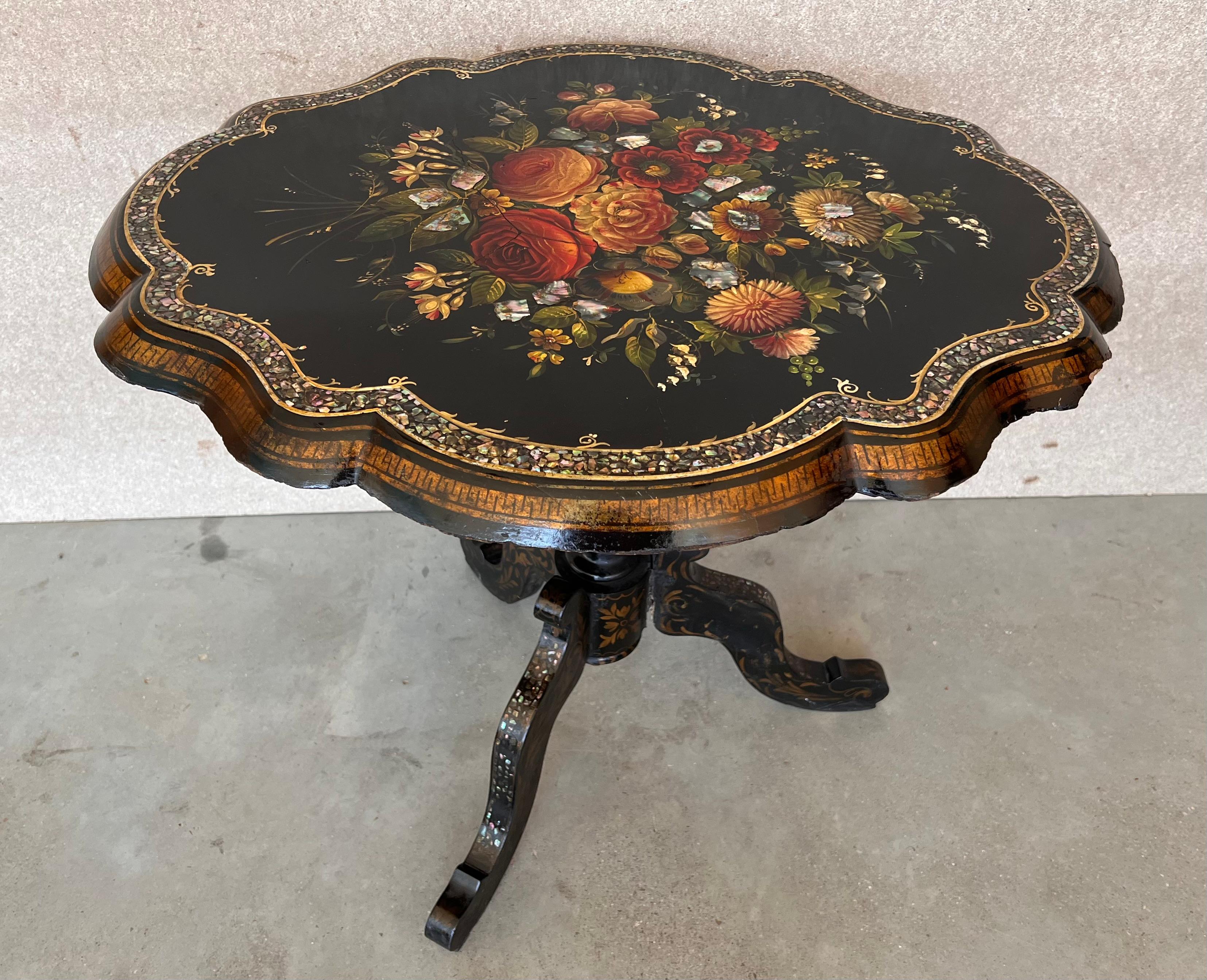 An antique English lacquer Papier Mâché tilt top occasional table, hand painted with floral motifs and inlaid with mother-of-pearl. The scalloped top and base made of paper-mache, that was fashion during the Victorian period. The spine is made of