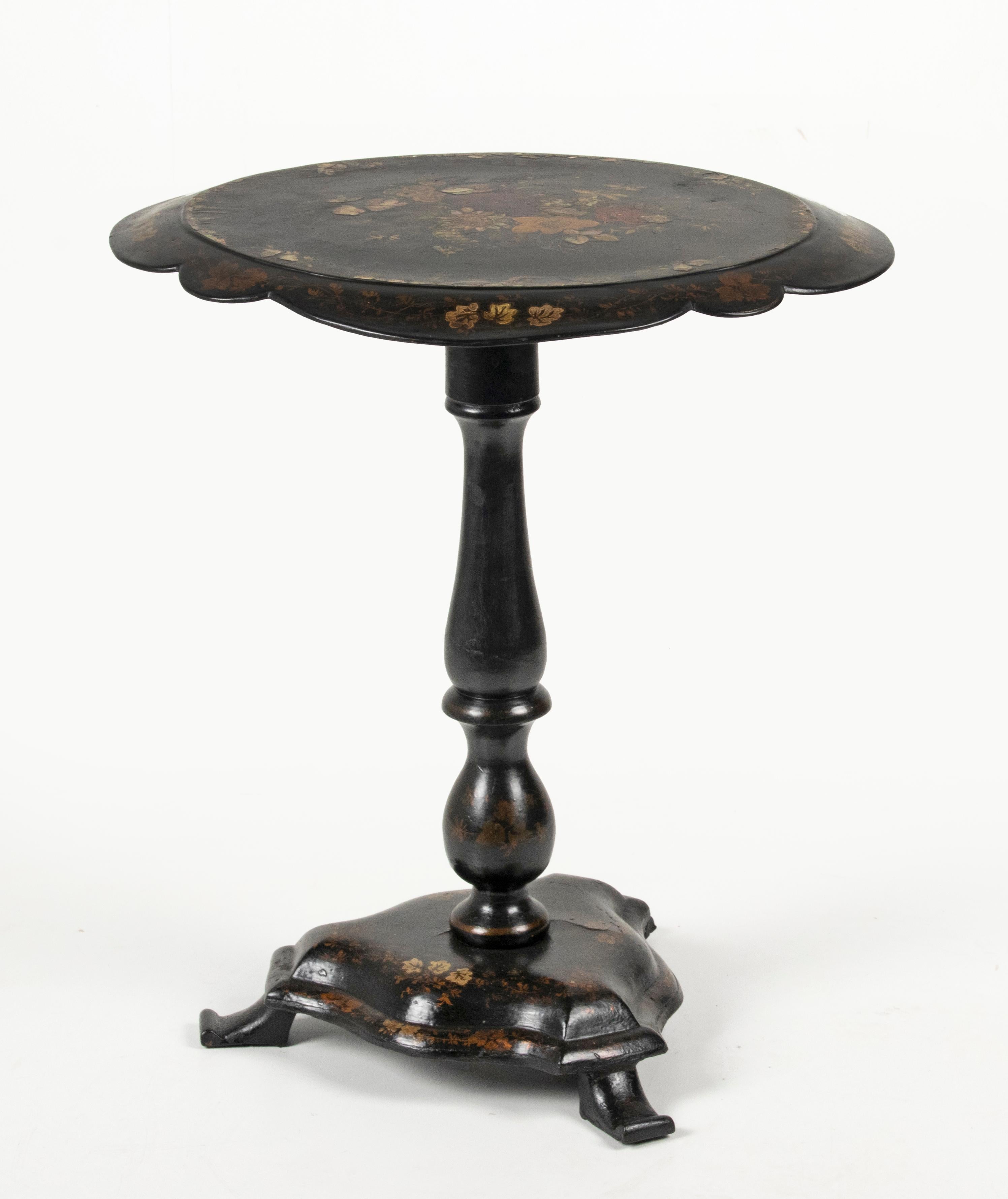 An antique English lacquer Papier Mâché tilt top occasional table, hand painted with floral motifs and inlaid with mother-of-pearl. The scalloped top and base made of paper-mache, that was fashion during the Victorian period. The spine is made of