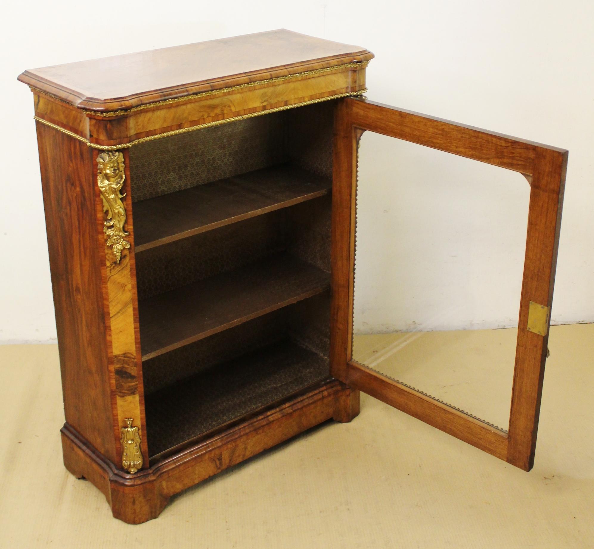 A superb quality Victorian period burr walnut pier cabinet. Of generous proportions and decorated throughout with tulip wood banding and crisp brass ormolu mounts. The single glazed door (lockable with key supplied) opens to access a shelved and