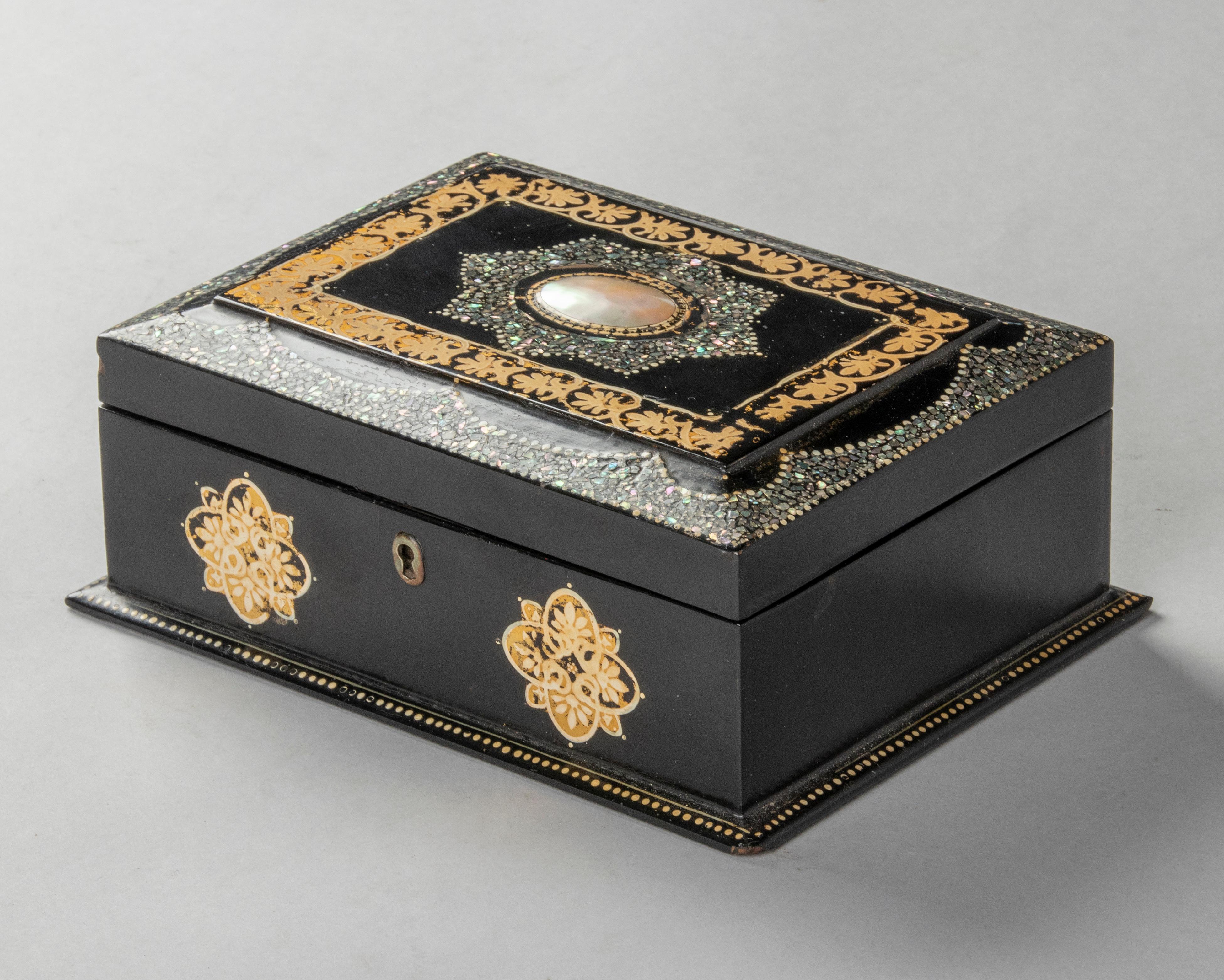 Beautiful antique Victorian jewelery box. The box is made of wood, covered with paper machee, lacquered black and inlaid with a mosaic of mother-of-pearl. Painted with gold colored decorations. The interior of the box is lined with blue silk fabric.