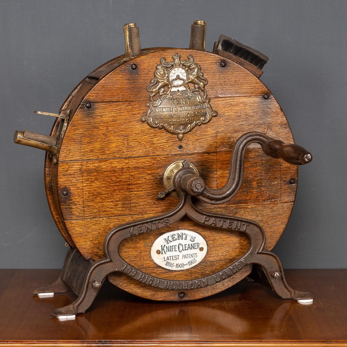 Antique 19th century Victorian knife sharpening and cleaning machine, manufactured by Kent's of London England. The machine consists of two whetstones in a solid oak casing with a heavy cast iron handle and sits on a heavy cast iron base. The top of