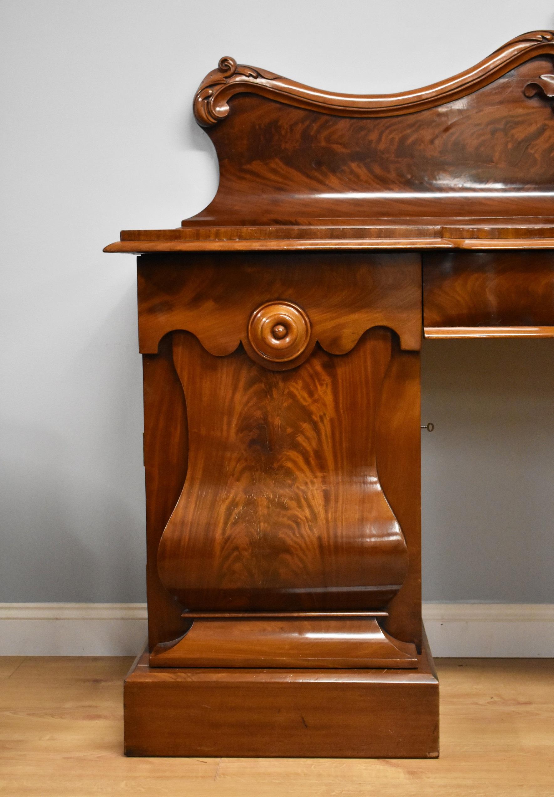 For sale is a fine quality Victorian Mahogany pedestal sideboard, having an ornately shaped and carved back, above a serpentine shaped top, having a large drawer to the centre. The top fits onto two pedestals, each having beautifully figured flame