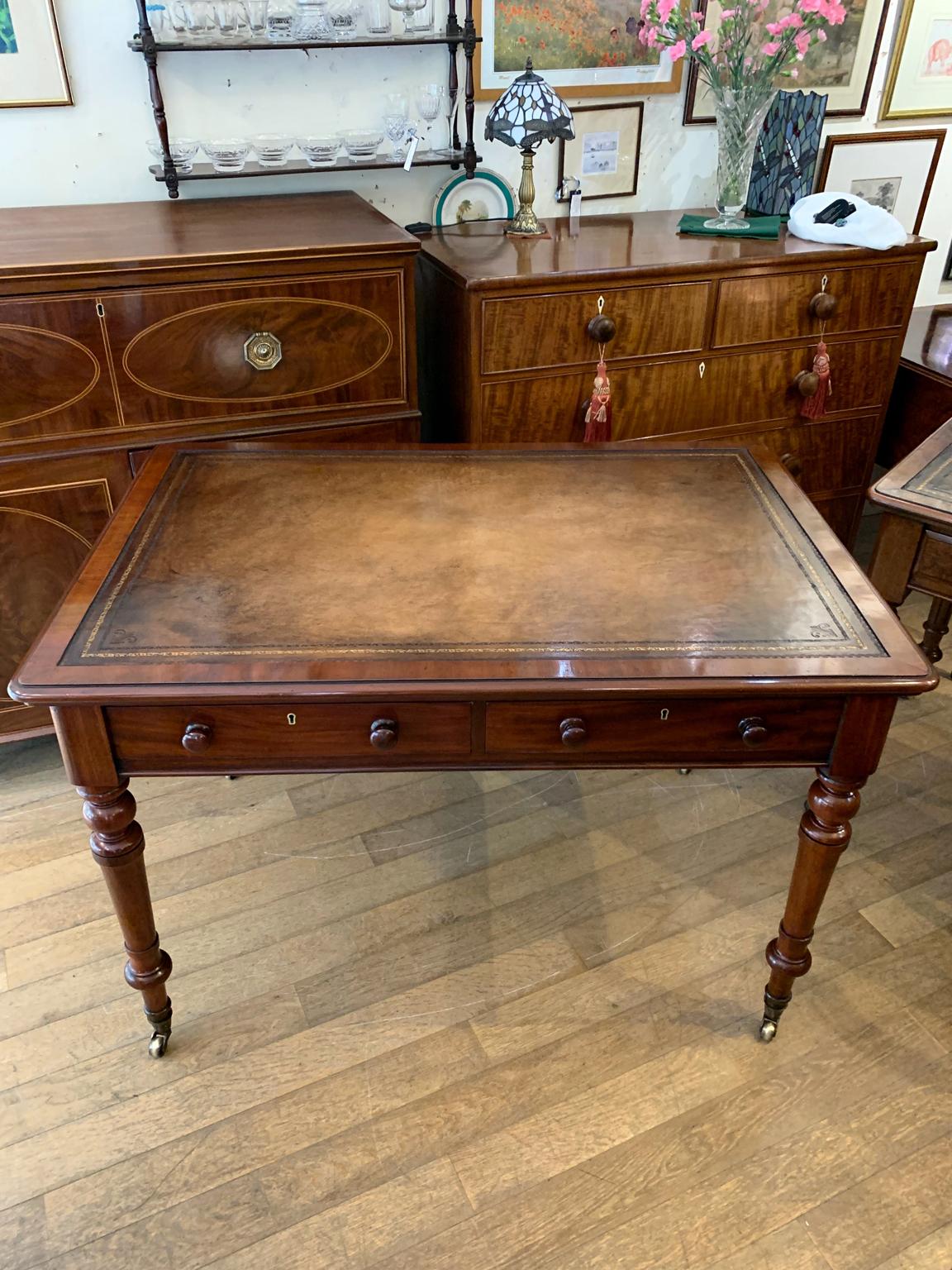 19th Century Victorian Mahogany writing table with two drawers and working keys. On turned legs, with brass original castors to base.
