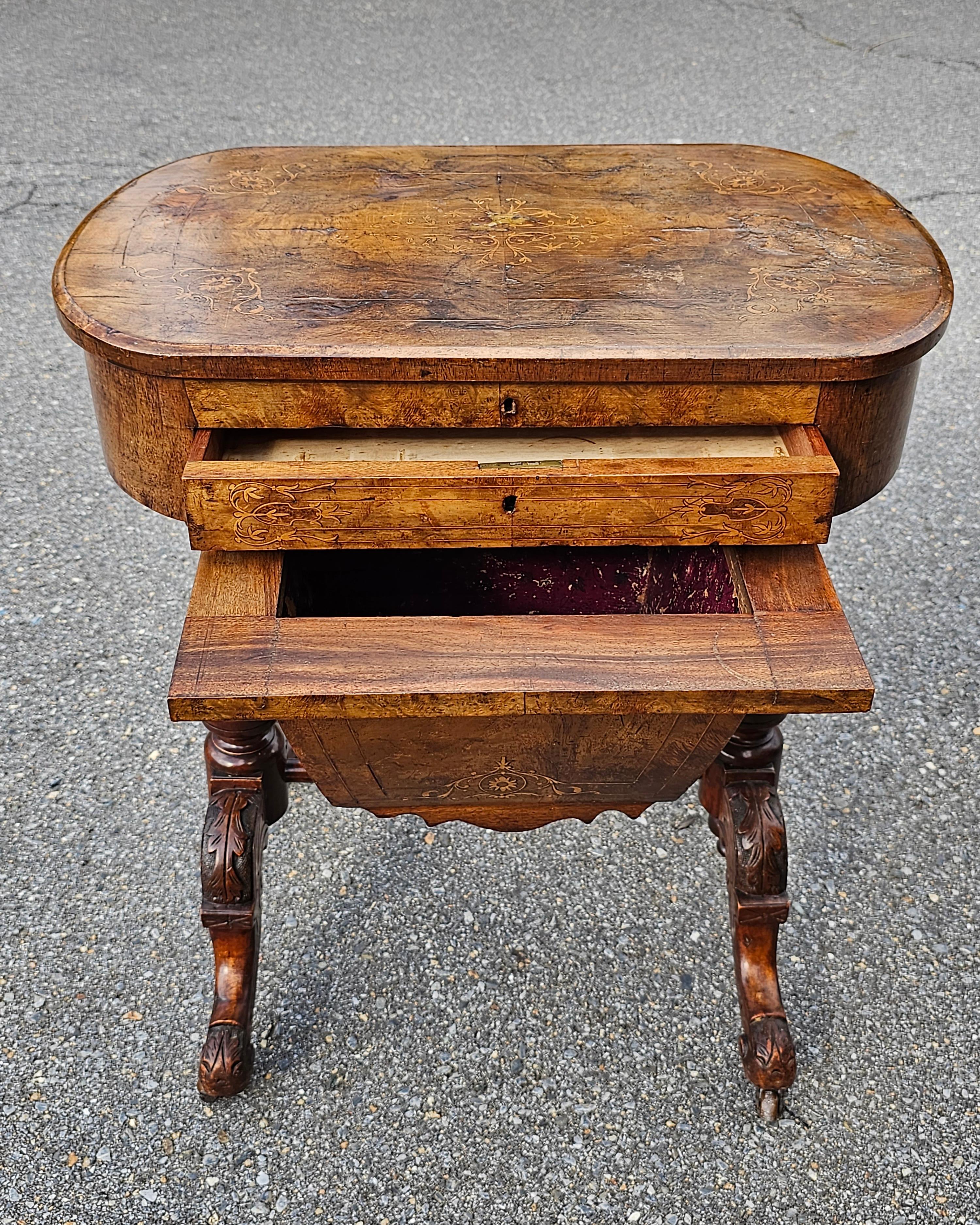 A 19th Century Victorian Walnut and Marquetry Burl sewing table with plenty 9f storage and on Wheels. Measures 24.25