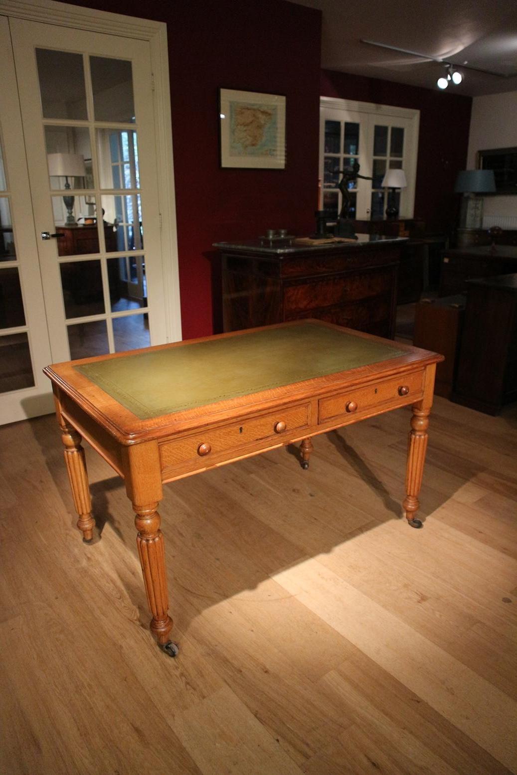 Beautiful Victorian antique oak writing table with 2 drawers. Entirely in perfect condition. The table has a green leather top and stands on porcelain wheels. The table is a freestanding model. Because the back is finished, the table can also stand