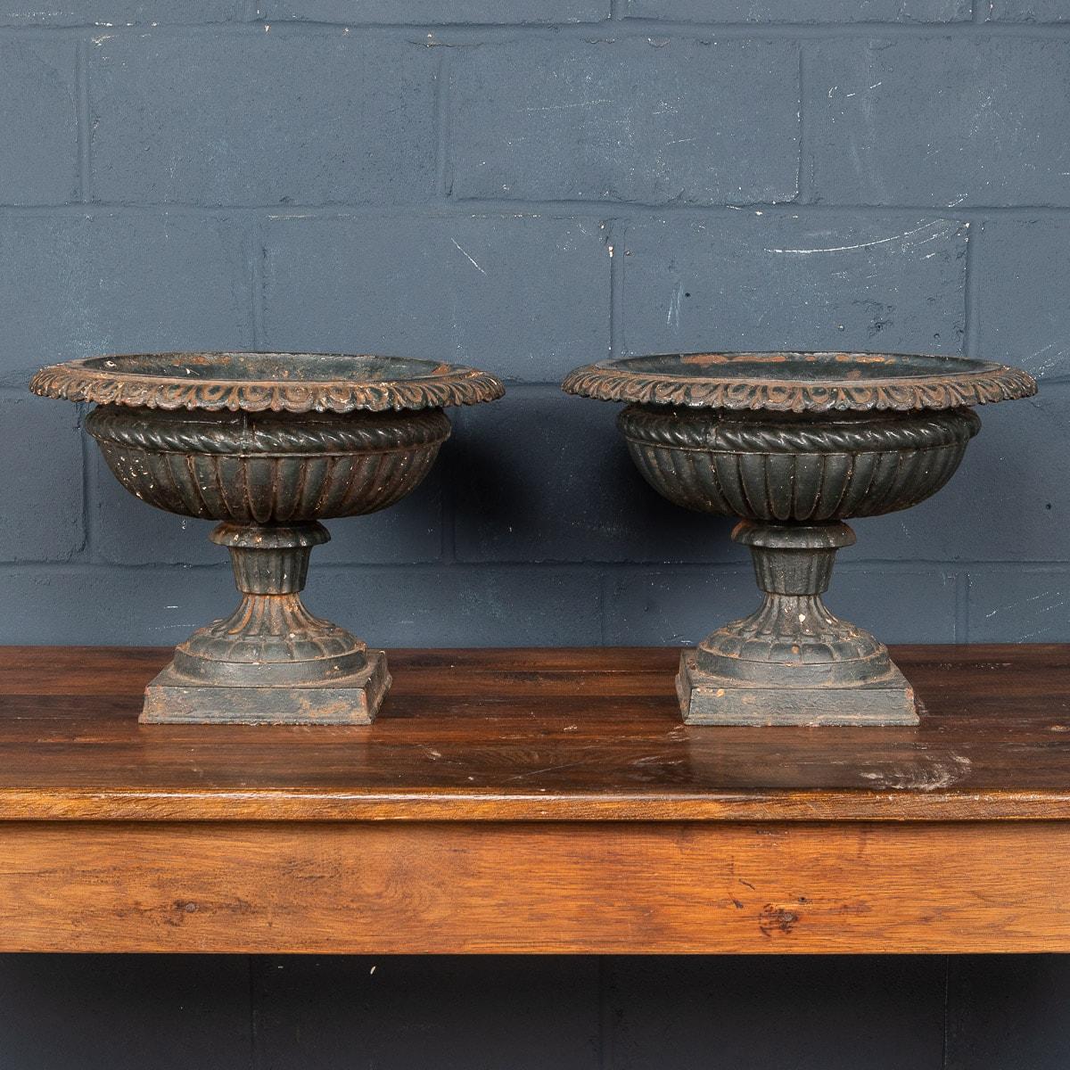 A large pair of late Victorian English cast iron garden urns dating to the latter part of the 19th century. Of neoclassical shape, they are in lovely condition, repainted over the years which merely adds their character and charm. 

CONDITION
In