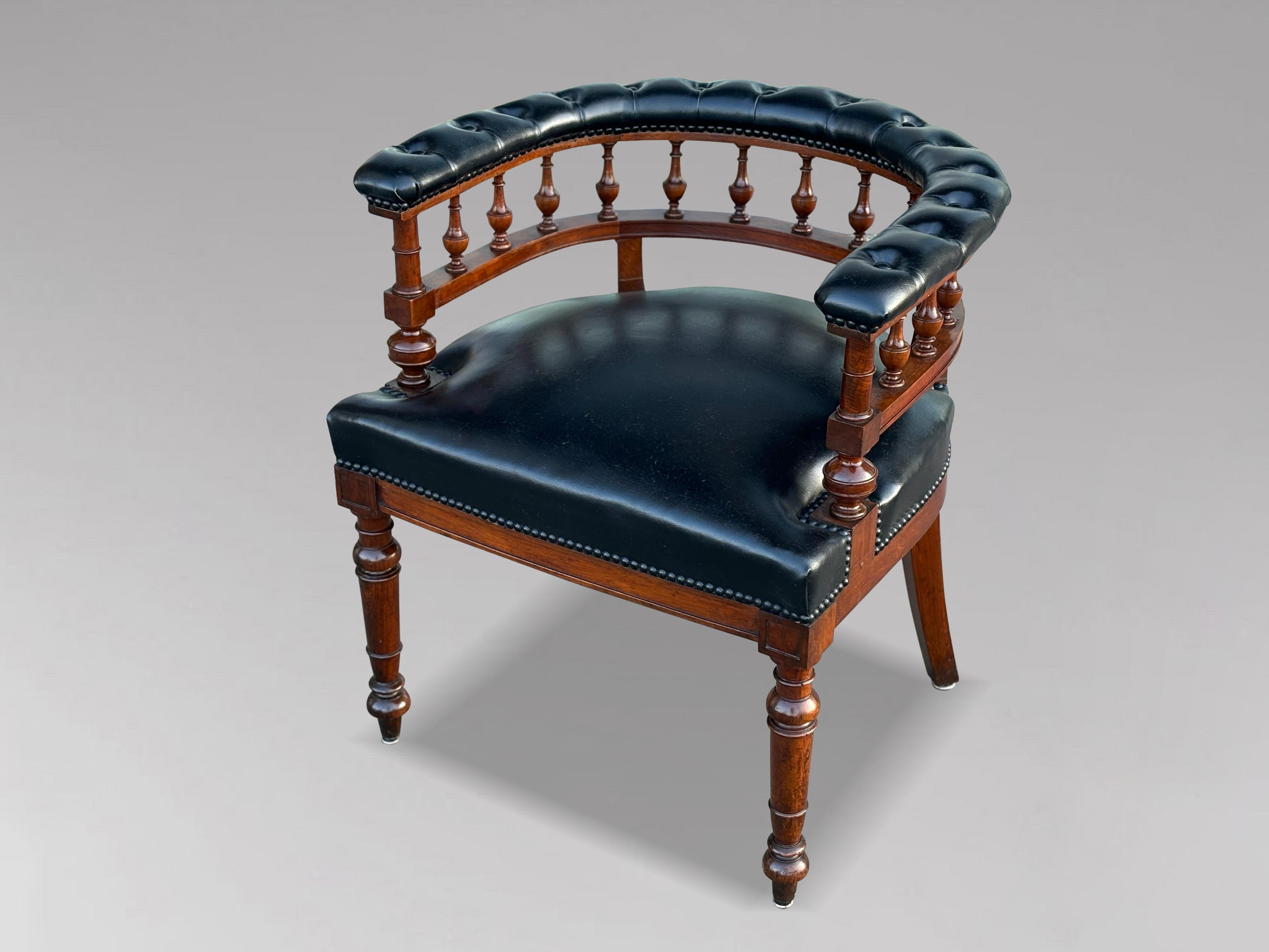 This fine quality late 19th-century Victorian period black leather and mahogany captain's office armchair, dating to around 1890, is in excellent condition. The chair features an elegantly curved buttoned leather scroll back, complemented by a bank