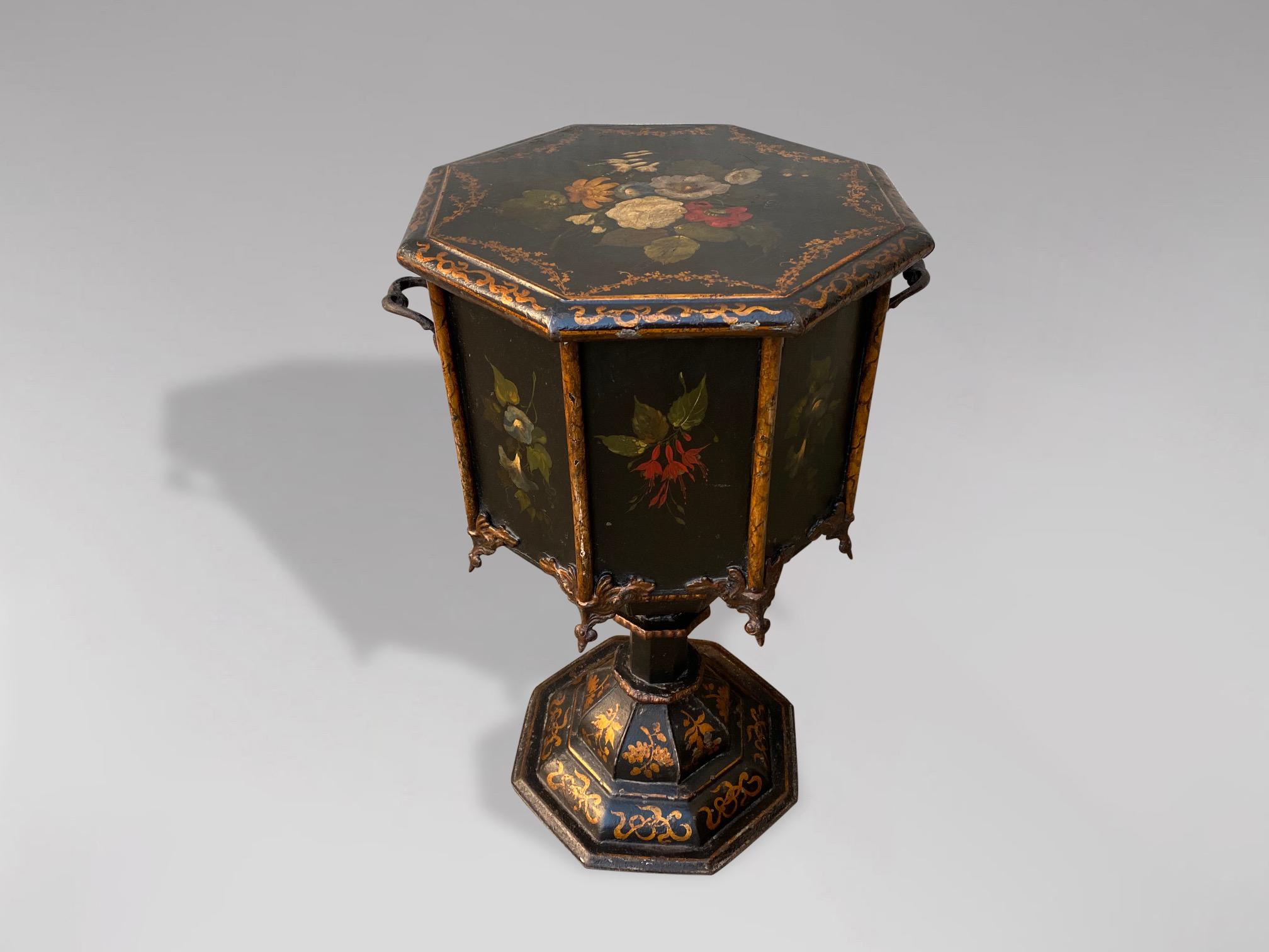 A stunning 19th century black painted octagonal English tole coal hod or scuttle with hinged lid. The entire box is painted in a glossy black and the top and front are decorated with hand painted floral motifs within a raised border with fine gold
