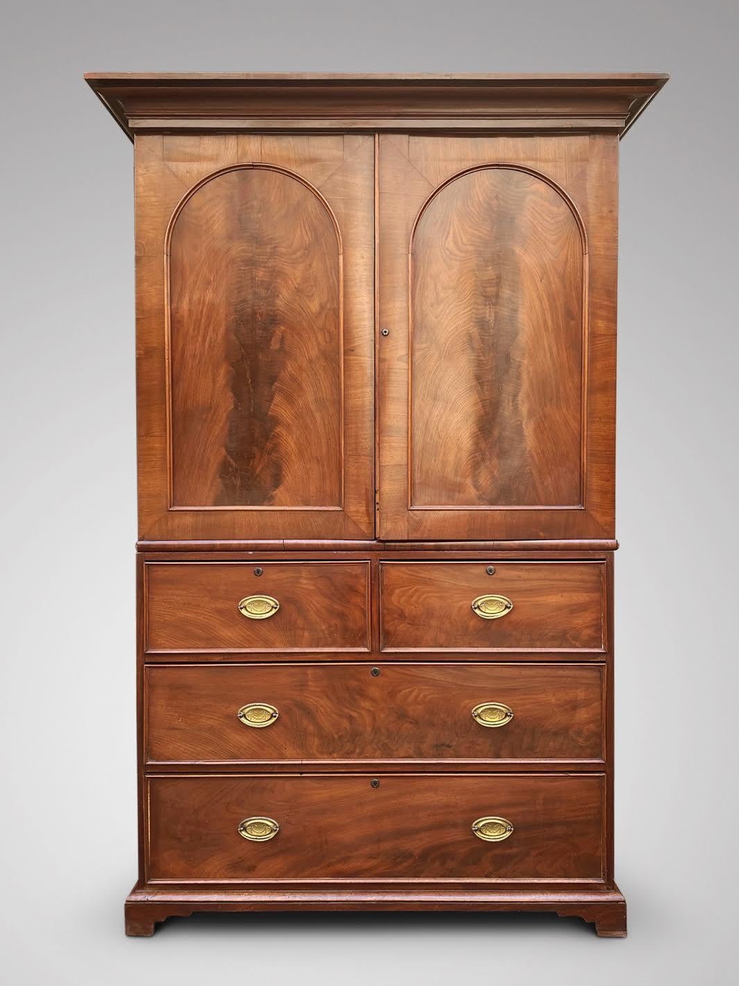 A good quality mid 19th century mahogany linen press in a rich light honey colour, with arched shaped doors that open to two fully sliding drawers that slide out , the lower section with two small and two long graduated drawers brass plate handles,