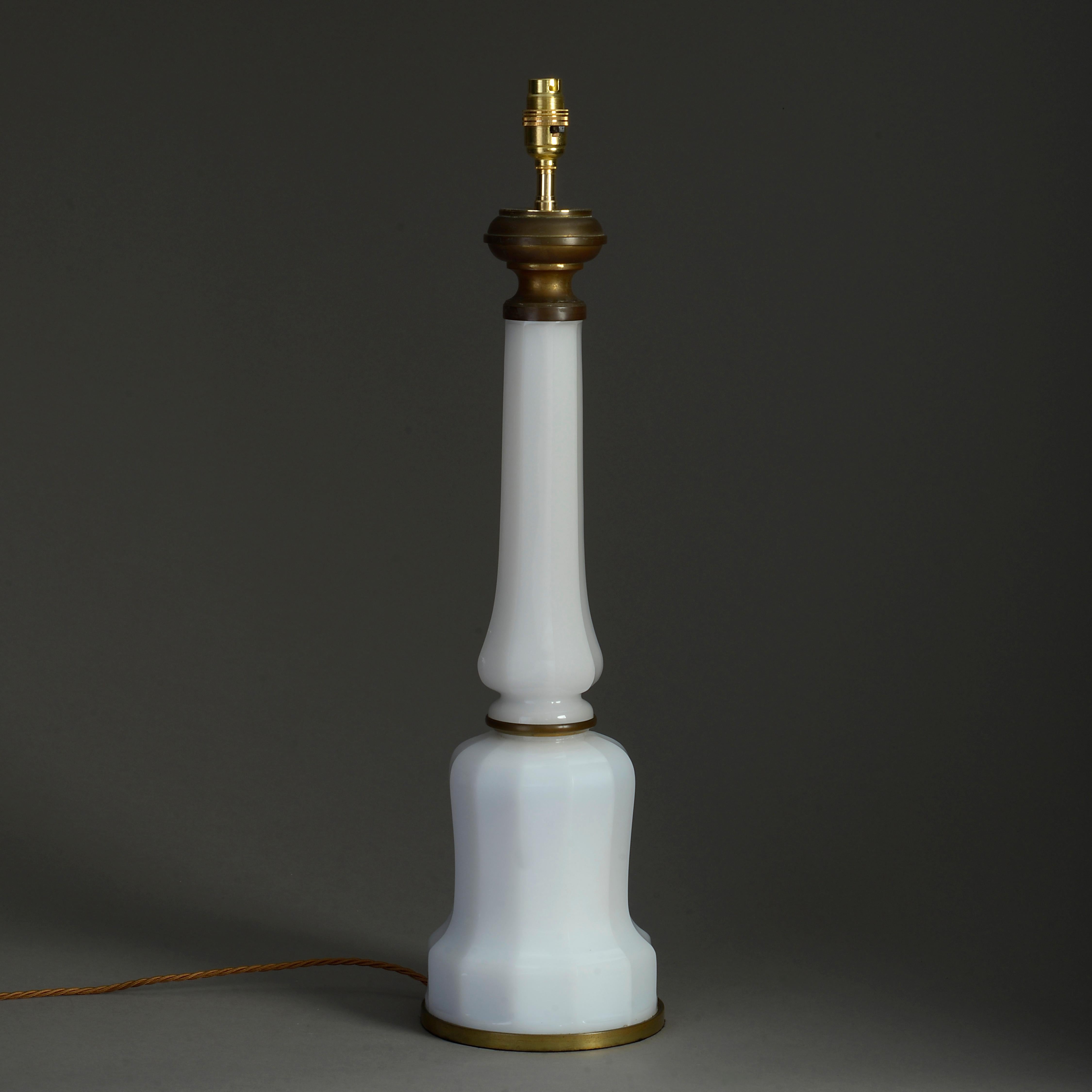 A mid-nineteenth century early Victorian Period white opaline glass lamp base, of shaped, faceted mallet form, having a brass top, collar and base.

Wired as an electric lamp. Dimensions refer to antique elements only.

Shade not included.