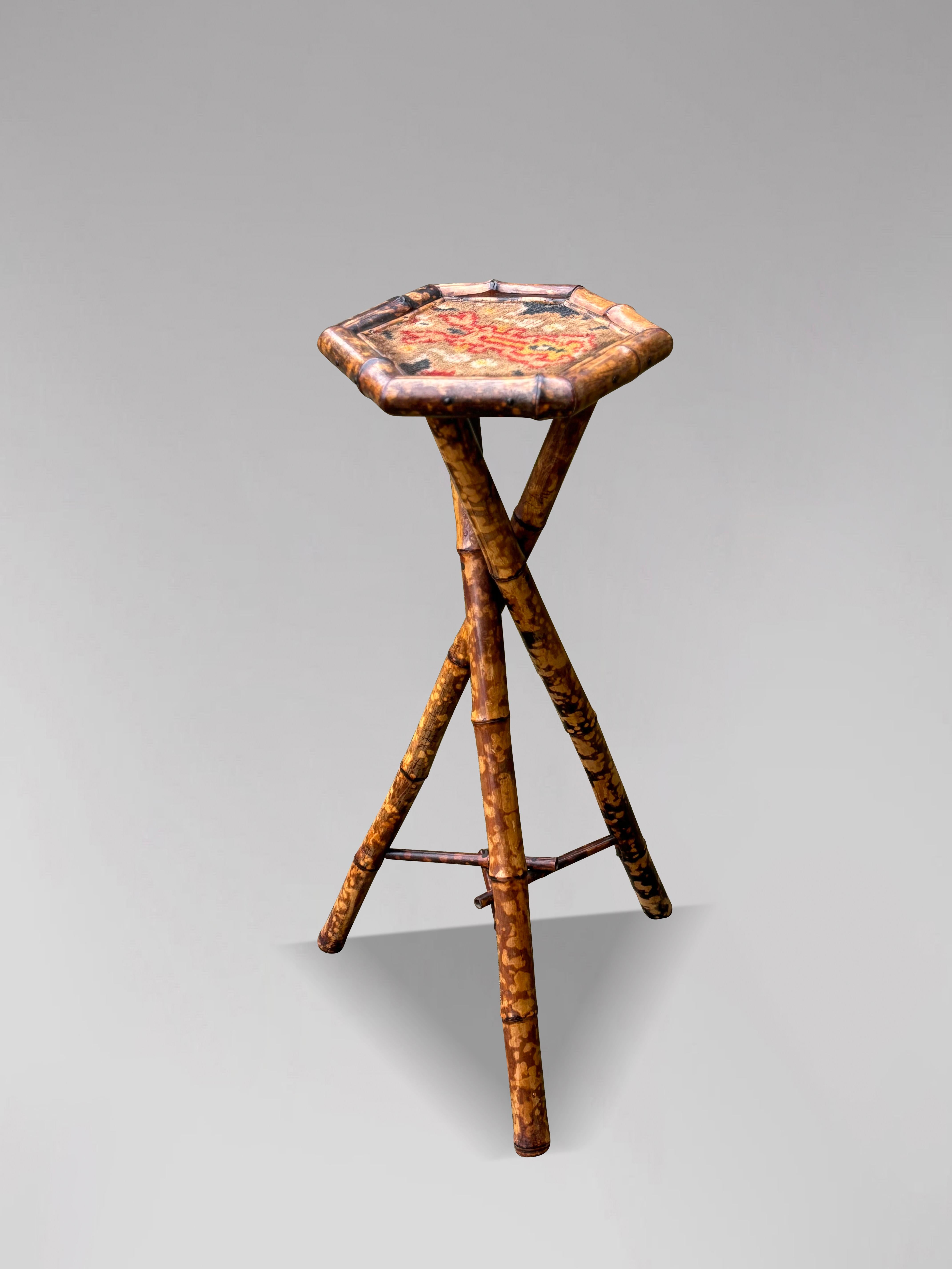 A late 19th century Victorian period tiger bamboo plant stand or tall table. Hexagonal top with border detail raised on a bamboo tripod base with twisted cross section leg formation united by stretchers. Great patina.

The dimensions are:
Height: