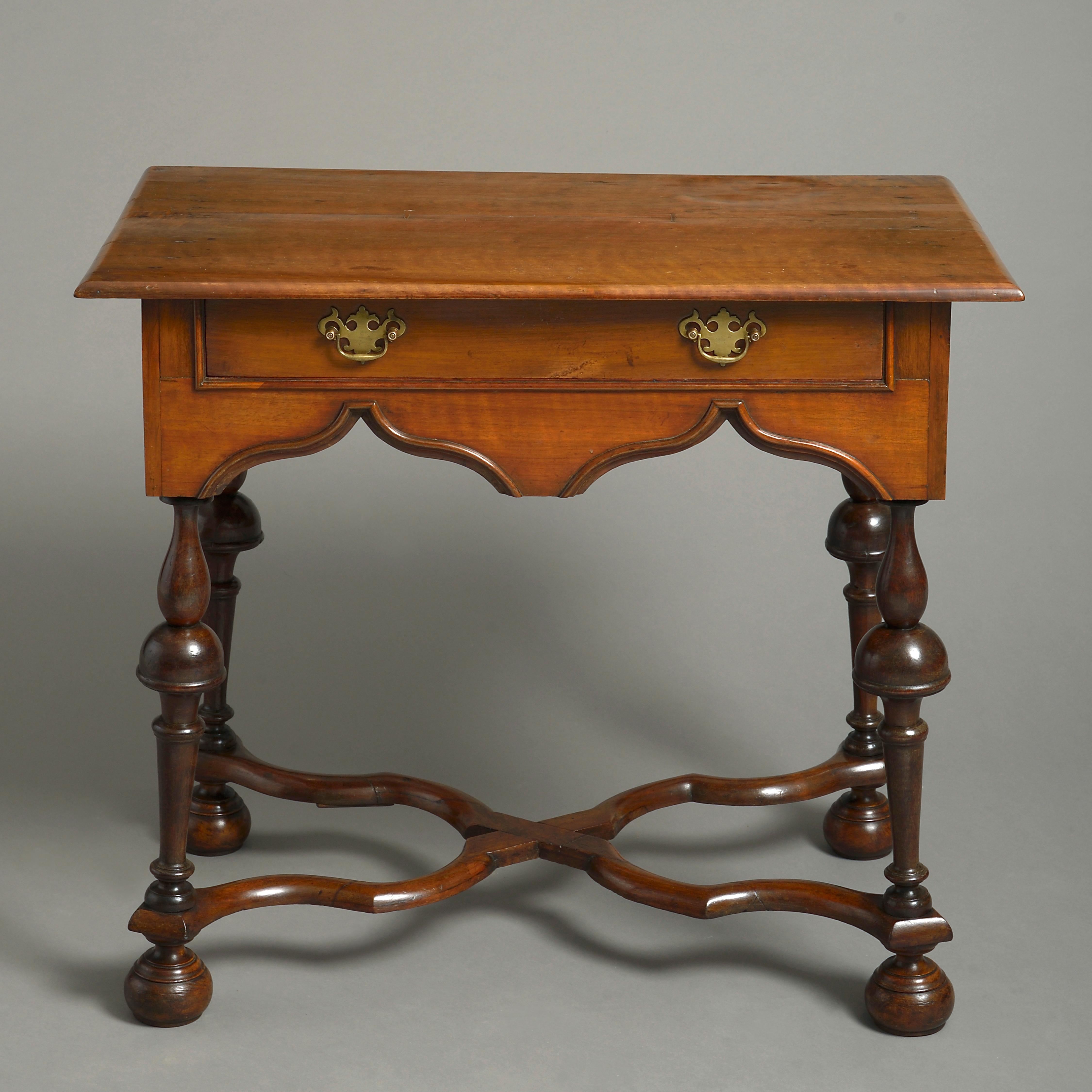 A late 19th century side table in the late 17th century Charles II manner, of soft faded colour, the overhanging top above a shaped frieze with single drawer with brass handles, raised on turned baluster legs with X-form stretcher and bun feet.