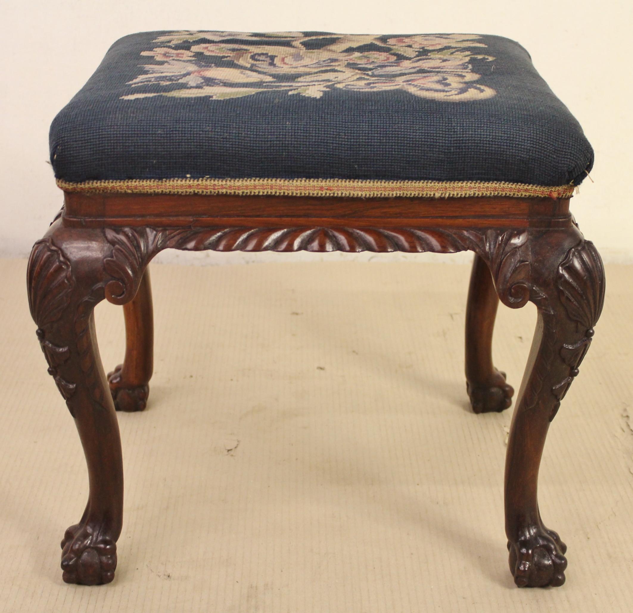 A charming Victorian period rosewood upholstered stool. Of fine construction in solid rosewood with an excellent color and patina. It is decorated throughout with crisply carved decorations and the cabriole legs terminate in 