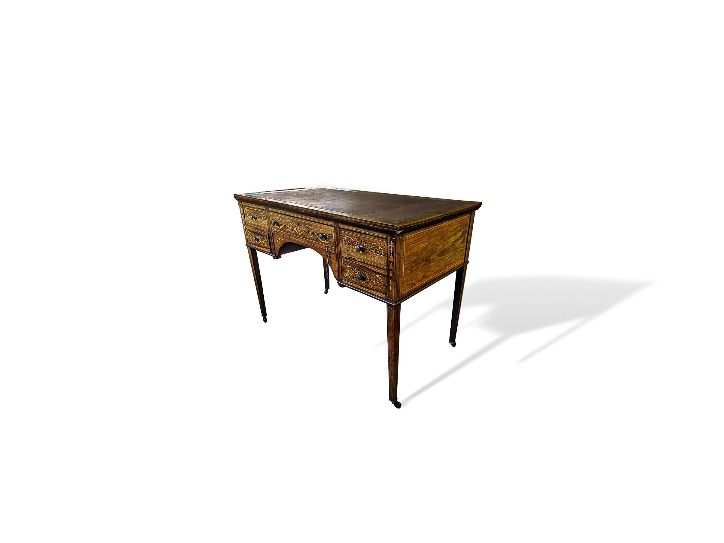 19th century Victorian rosewood writing desk with satinwood stringing and various Italianate marquetry and leather writing top, circa 1880. Slender tapered legs resting on original ceramic casters, drawers have original brass knob hardware and