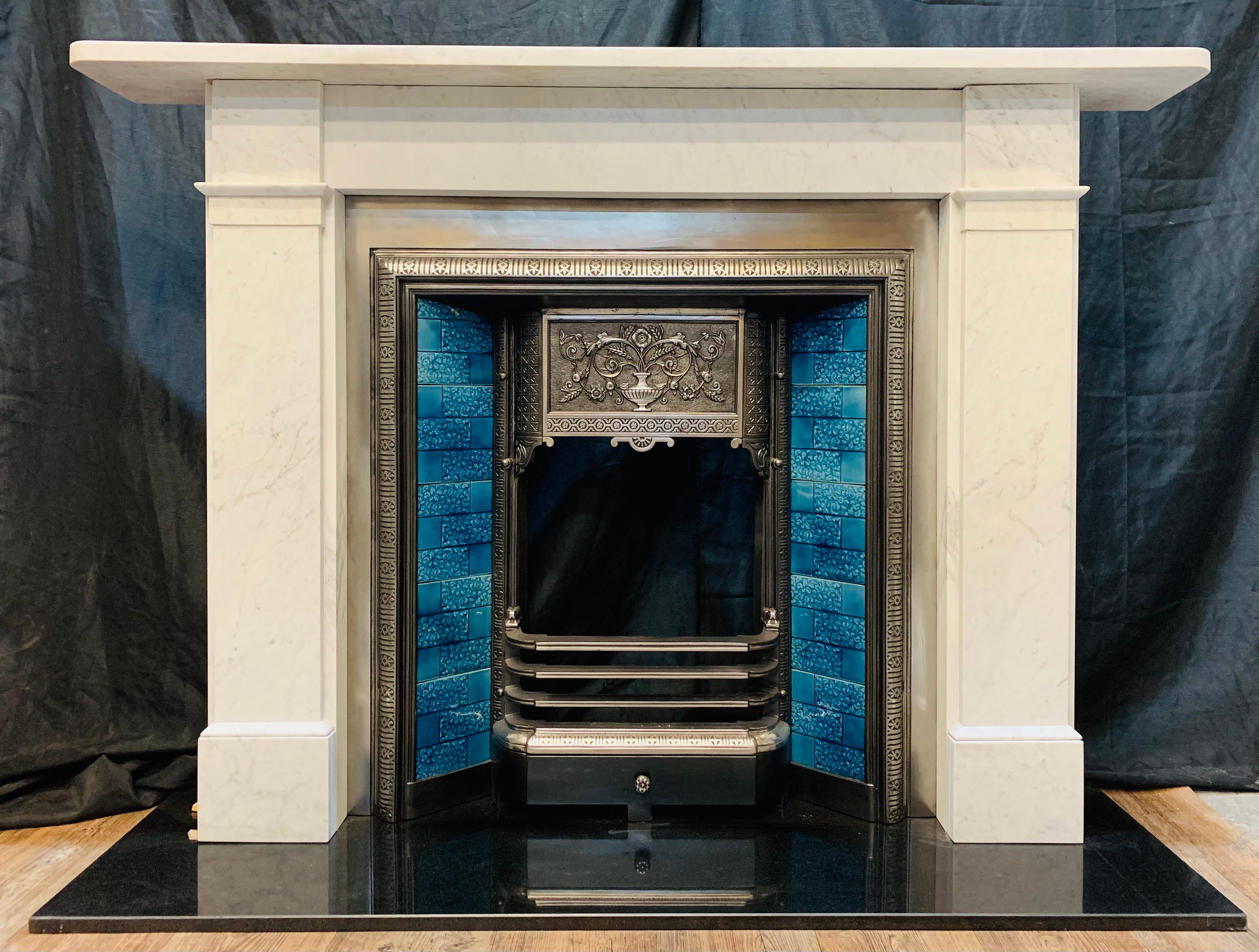 Un bel encadrement de cheminée polyvalent en marbre de Carrare écossais légèrement veiné, datant du XIXe siècle. Une étagère carrée aux angles arrondis surmonte une frise unie, flanquée de hauts jambages à gradins incorporant des insertions évasées