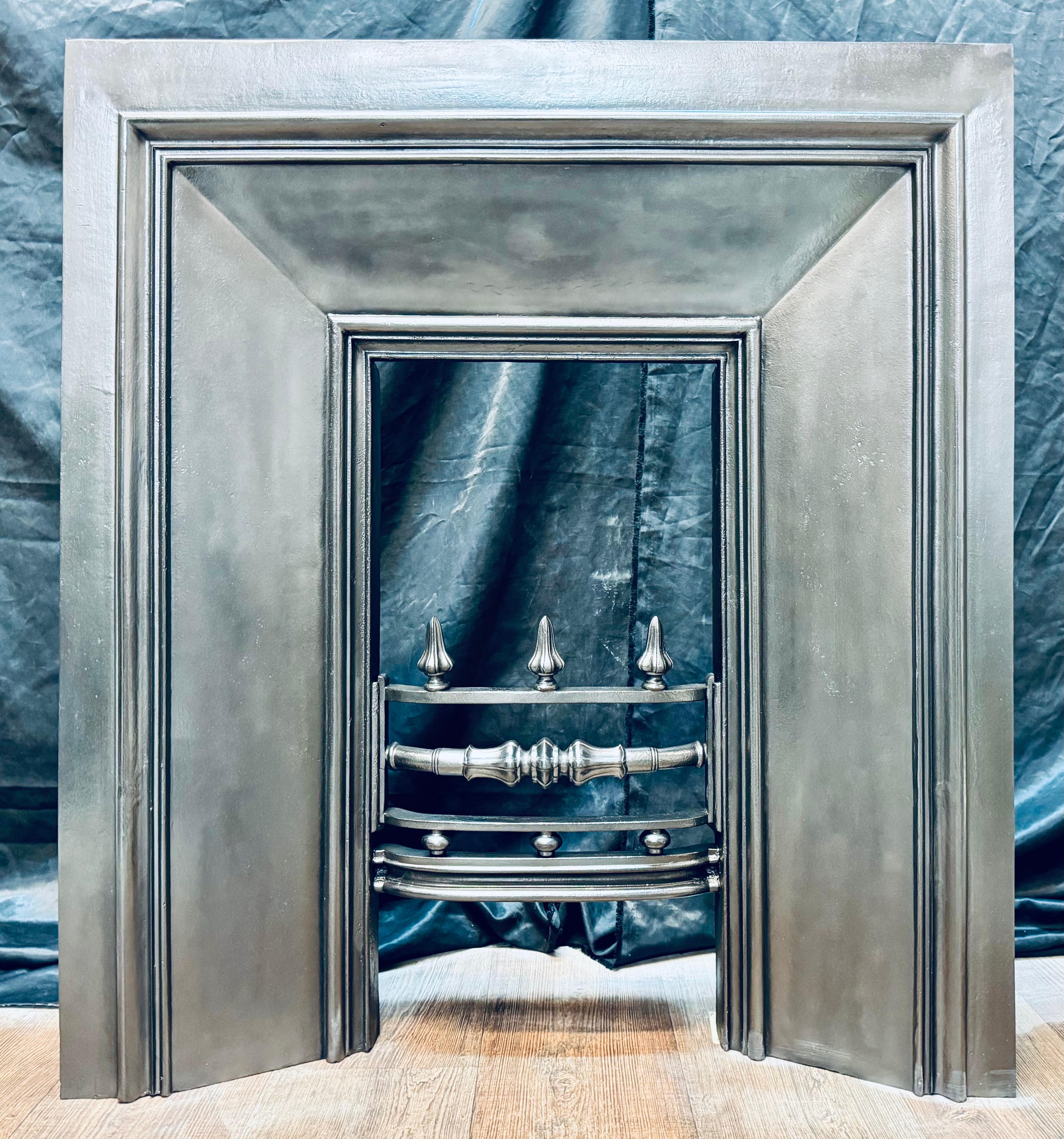 A simple Scottish 19th Century Victorian splayed cast iron fireplace insert by the renowned Carron of Falkirk foundry. 
An outer frame with a raised border splayed sides envelop to the fire opening. With a shaped fire front with three finials to the
