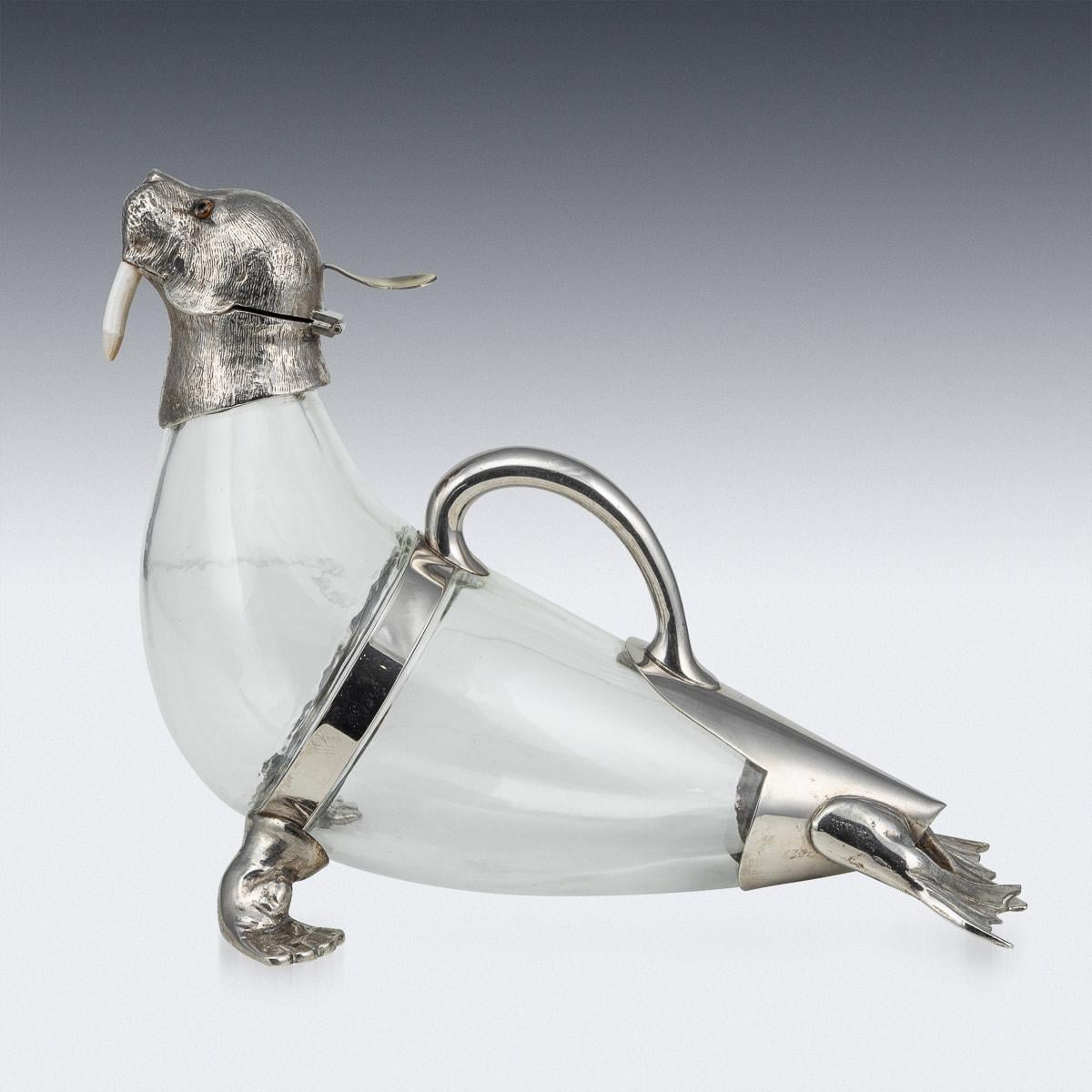 Antique 19th Century Victorian zoomorphic silver-plated and glass walrus wine jug is a true marvel of artistry and craftsmanship. This stunning piece seamlessly blends the elegance of silver with the delicacy of glass, resulting in a wine jug that