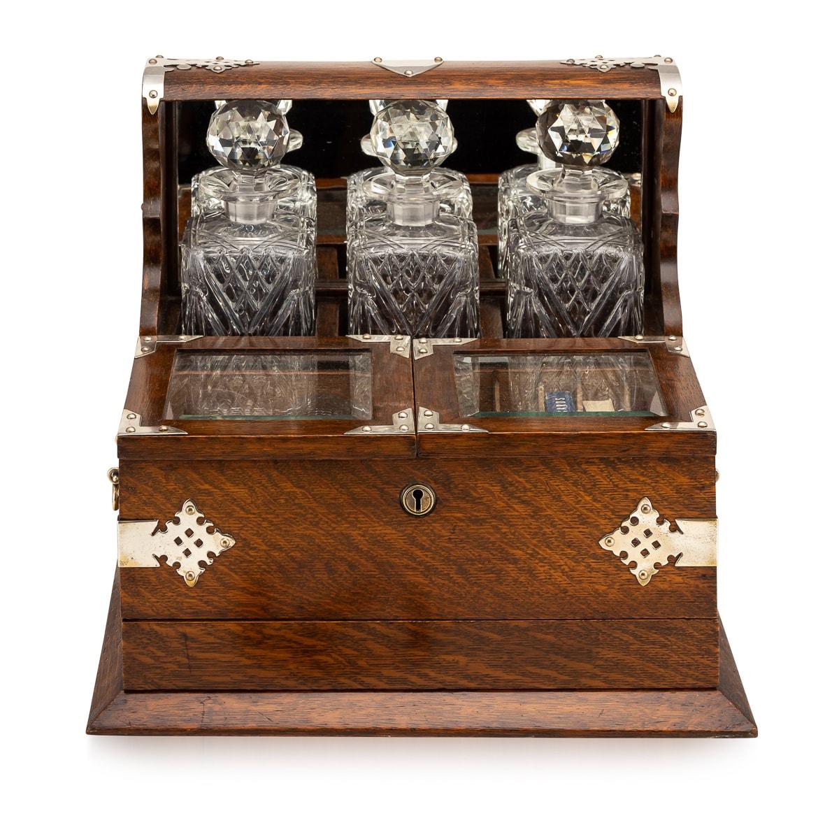 Antique late-19th Century Victorian silver plated mounted on solid oak tantilus, with a humidor & games compendium, the interior comprising three cut crystal decanters with stoppers, three glasses, a secret hidden draw, which opens by first opening