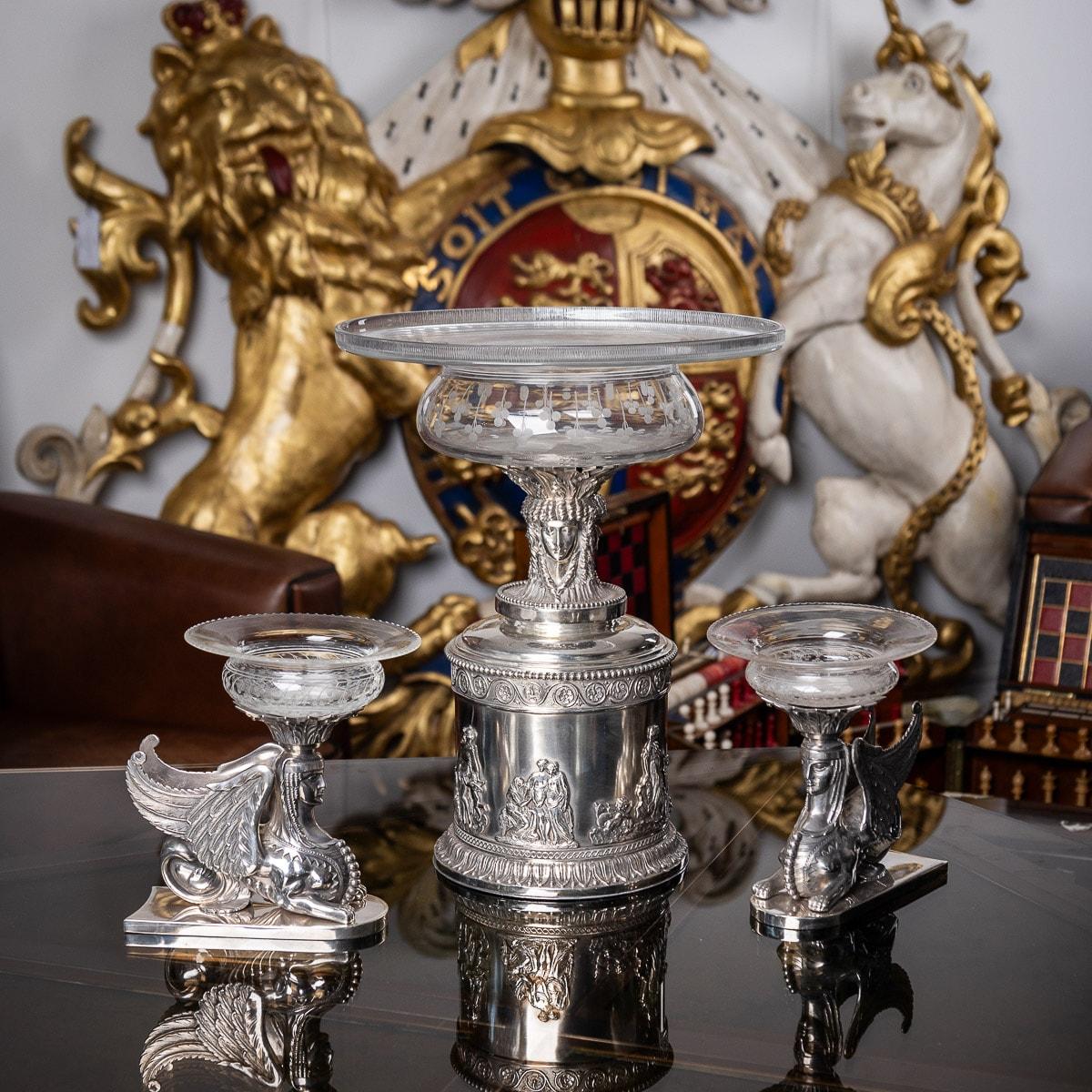 Antique 19th century rare and magnificent Victorian solid silver three-piece table garniture, the cylindrical central piece applied with a cast Neoclassical frieze depicting mythological figures, surmounted by a triple-headed Greek goddess, the