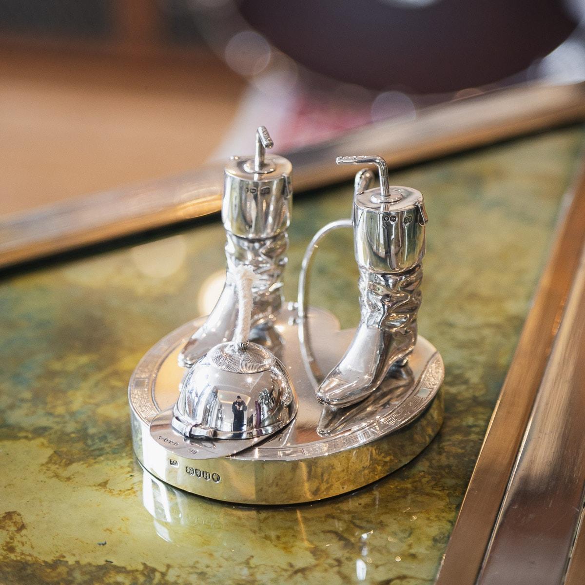Antique 19th century Victorian solid silver table lighter, on a hoof stepped base, mounted with two jockey boots with a whip shaped lighter inserts, the jockey cap mounted with a wick and spur shaped handle. Hallmarked English Silver (925 standard),