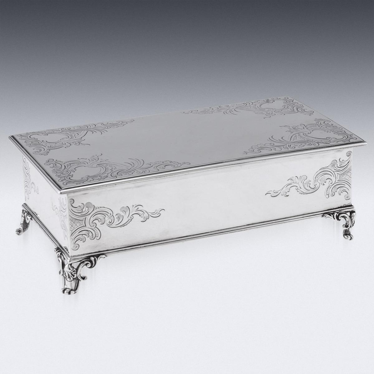 19th Century Victorian silver large lidded inkstand, of rectangular casket form, with a hindged lid, engraved with Rococo scrolls and foleage, with vacant cartooches, resting on four cast scroll feet, inside mounted wit twin cut glass and silver