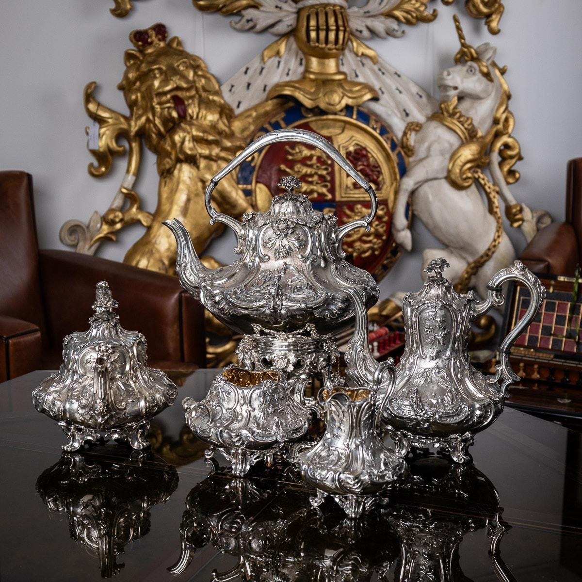 19th Century Victorian silver five piece tea service, consisting of a kettle, coffee pot, teapot, sugar bowl, cream jug, each lobed body resting on four scroll feet, profusely embossed with scrolls and flowers and one side decorated in Orientalist