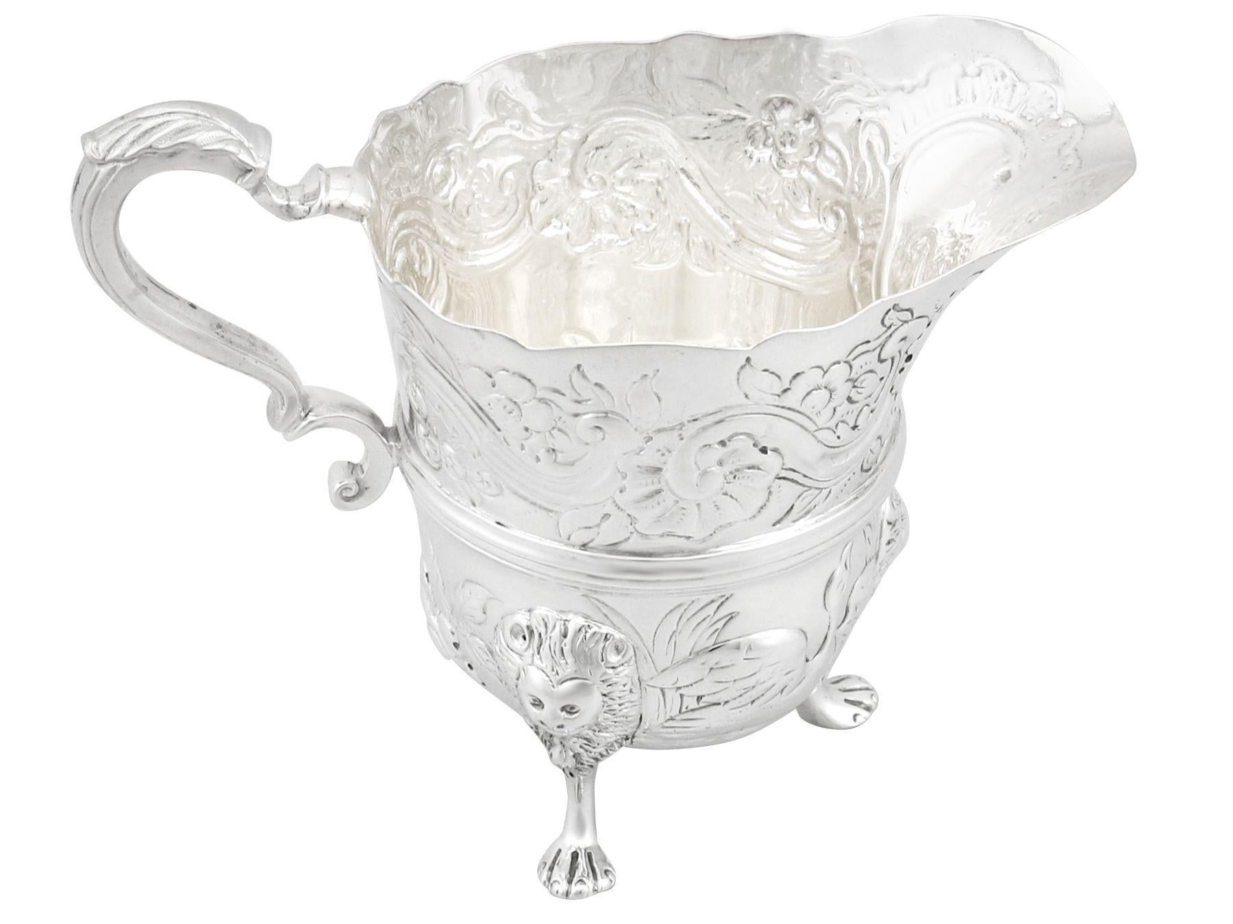 This fine antique Victorian sterling silver cream jug has a plain circular inverted bell shaped form, in the classic Georgian Irish style.

The body of this Victorian cream jug is embellished with chased floral and scrolling foliate designs above
