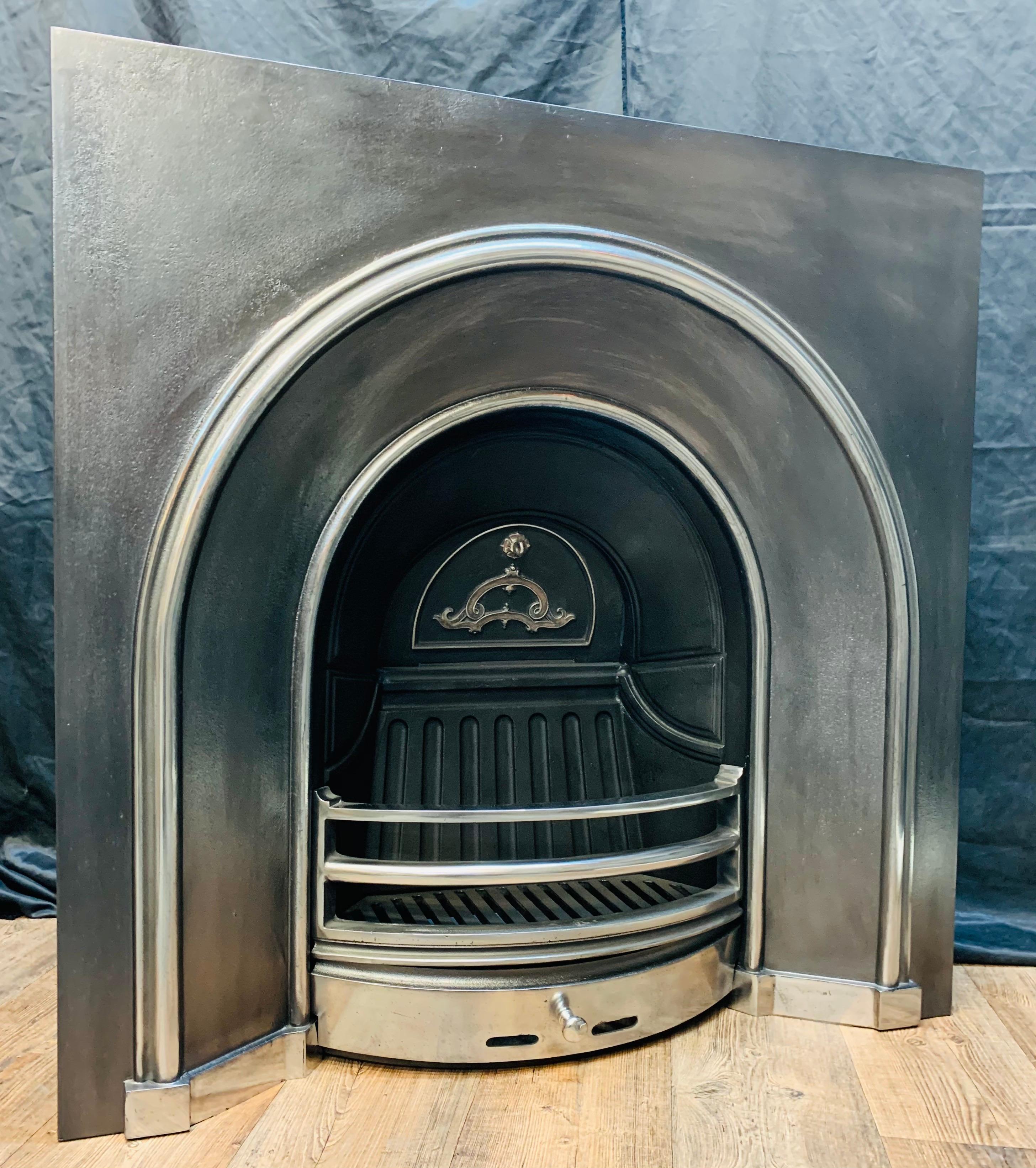 A large and versatile 19th century Victorian style cast iron large aperture arch fireplace insert. A generous outer plate with a polished and highlighted raised moulding sweeping in towards an arch grate with ornate damper plate and a set of three