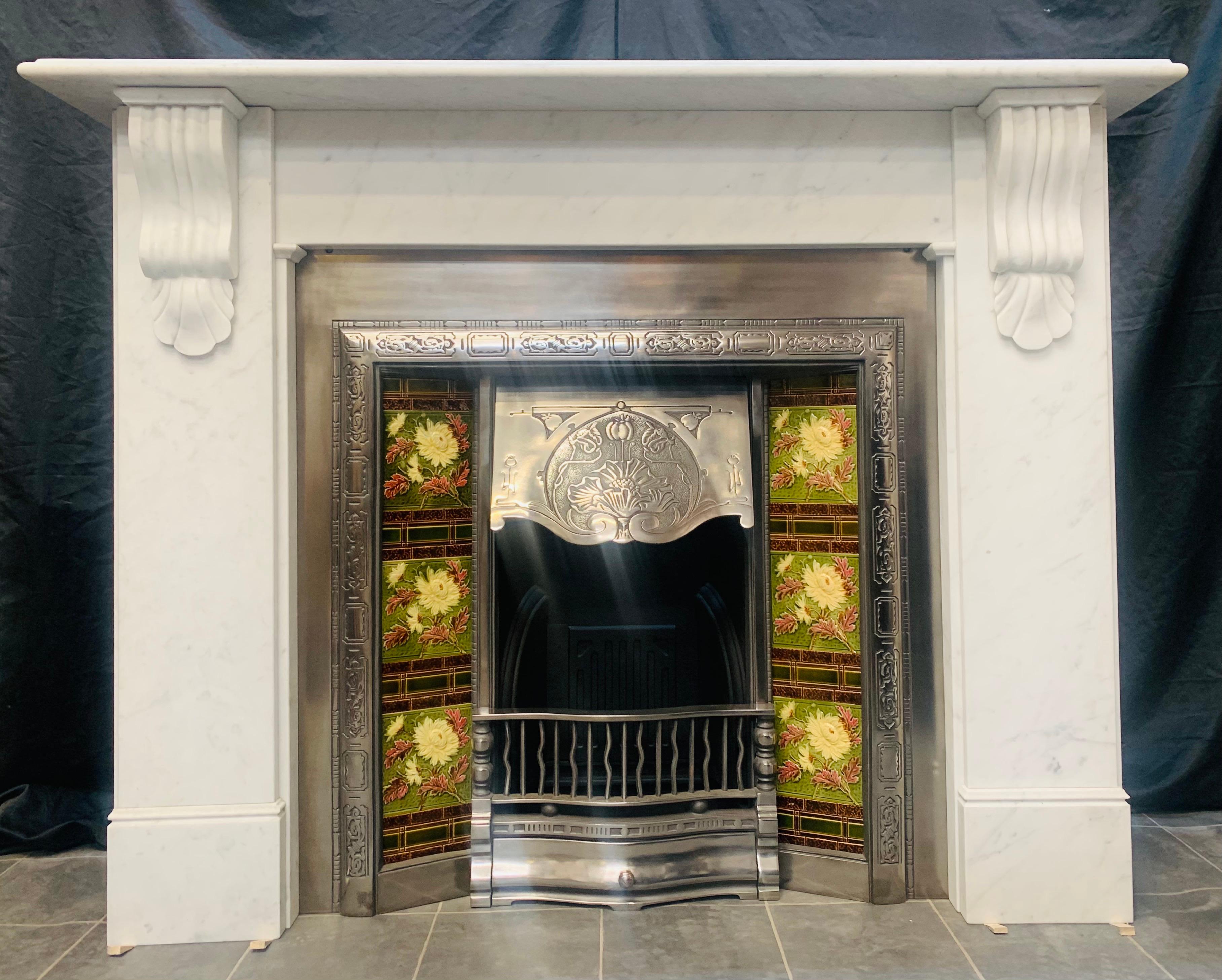 A versatile and fairly large 19th century Victorian style Carrara marble fireplace surround. A scalloped shelf sits above an unadorned frieze, flanked by stepped jambs each hosting a well carved corbel and shell , all resting on moulded foot block