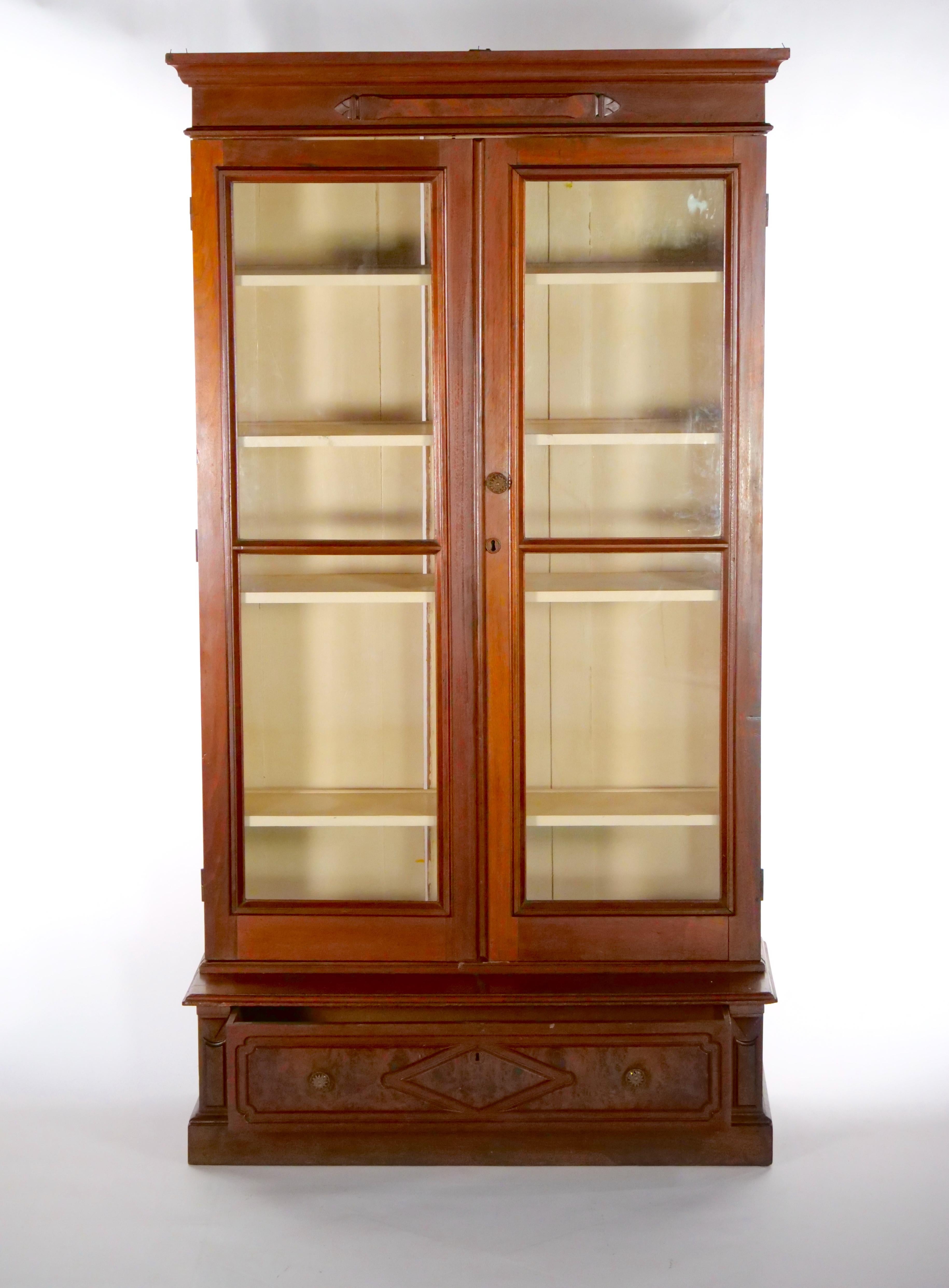 Early 19th century walnut wood Victorian style painted interior two door bookcase / cabinet with bottom front drawer. The bookcase is in good condition. The right door is bowed and not close completely flush. Original finish , breaks down to two