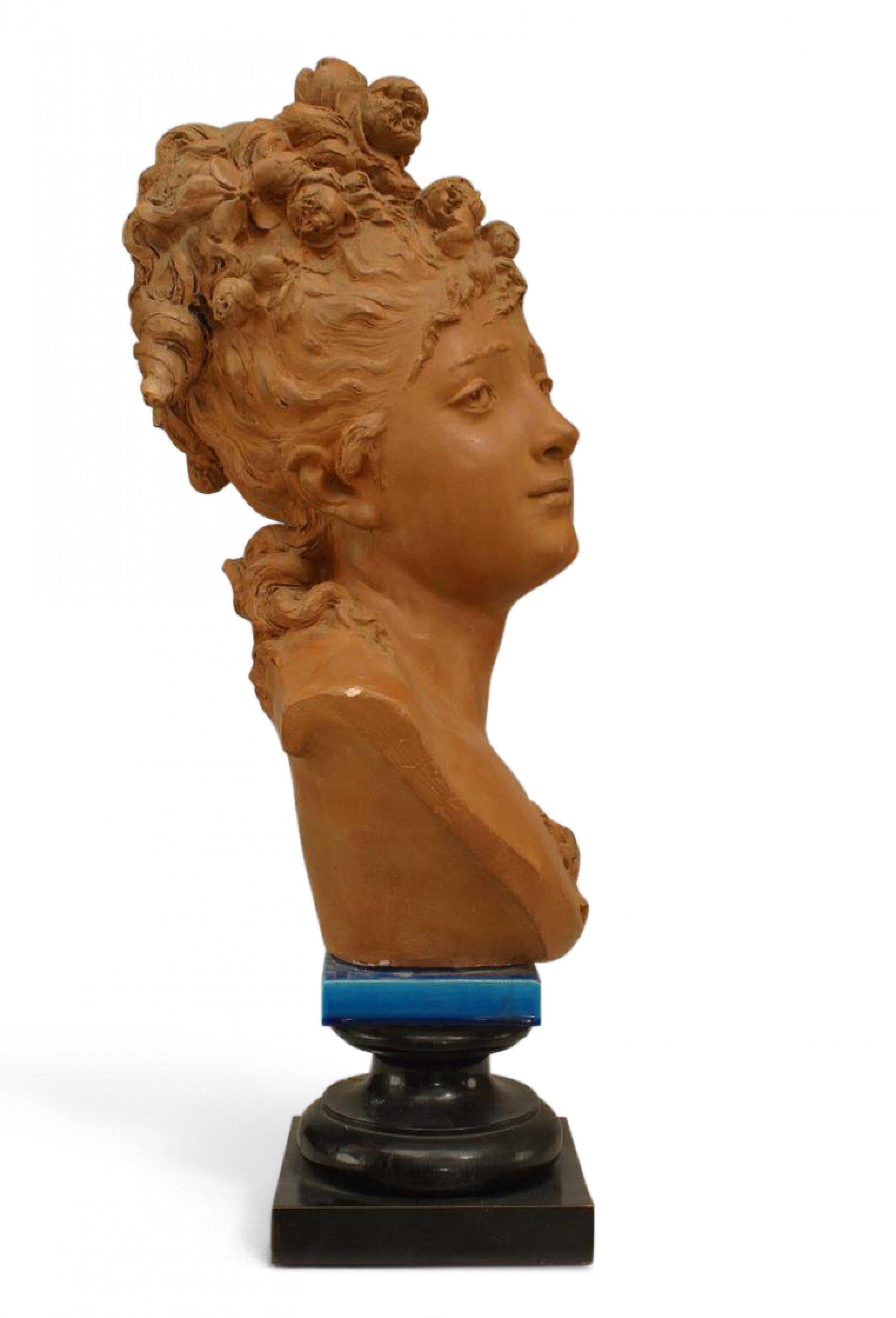 French Victorian terra cotta bust of 19th century lady with flowers in hair on blue porcelain & black painted square base (signed CARRIER BELLEUSE).
  