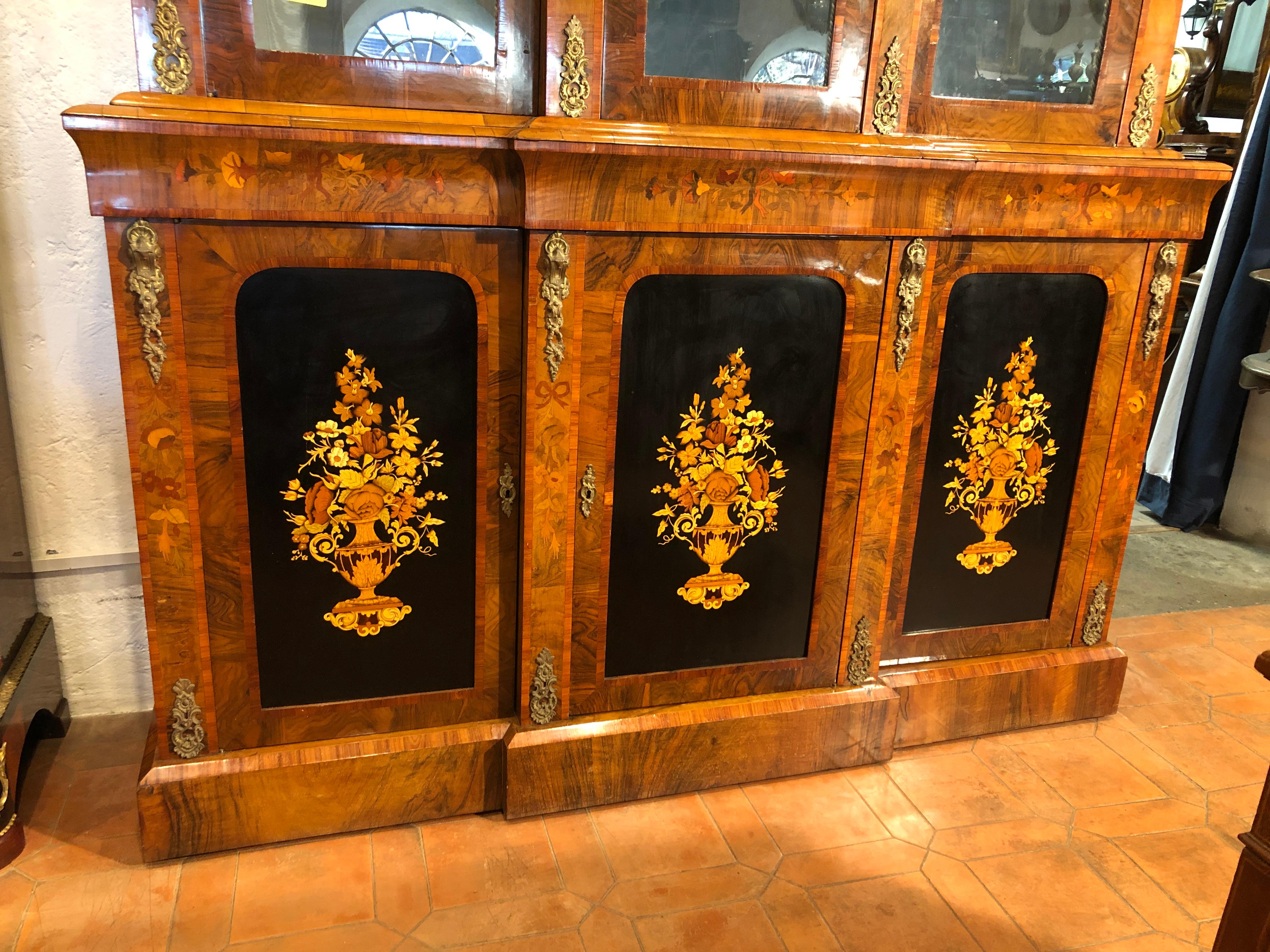 English bookcase with three doors, from the Victorian period, circa 1860, in walnut and inlaid with fruit woods. Applications in gilded bronze on the uprights of the doors. To be restored but in excellent condition.