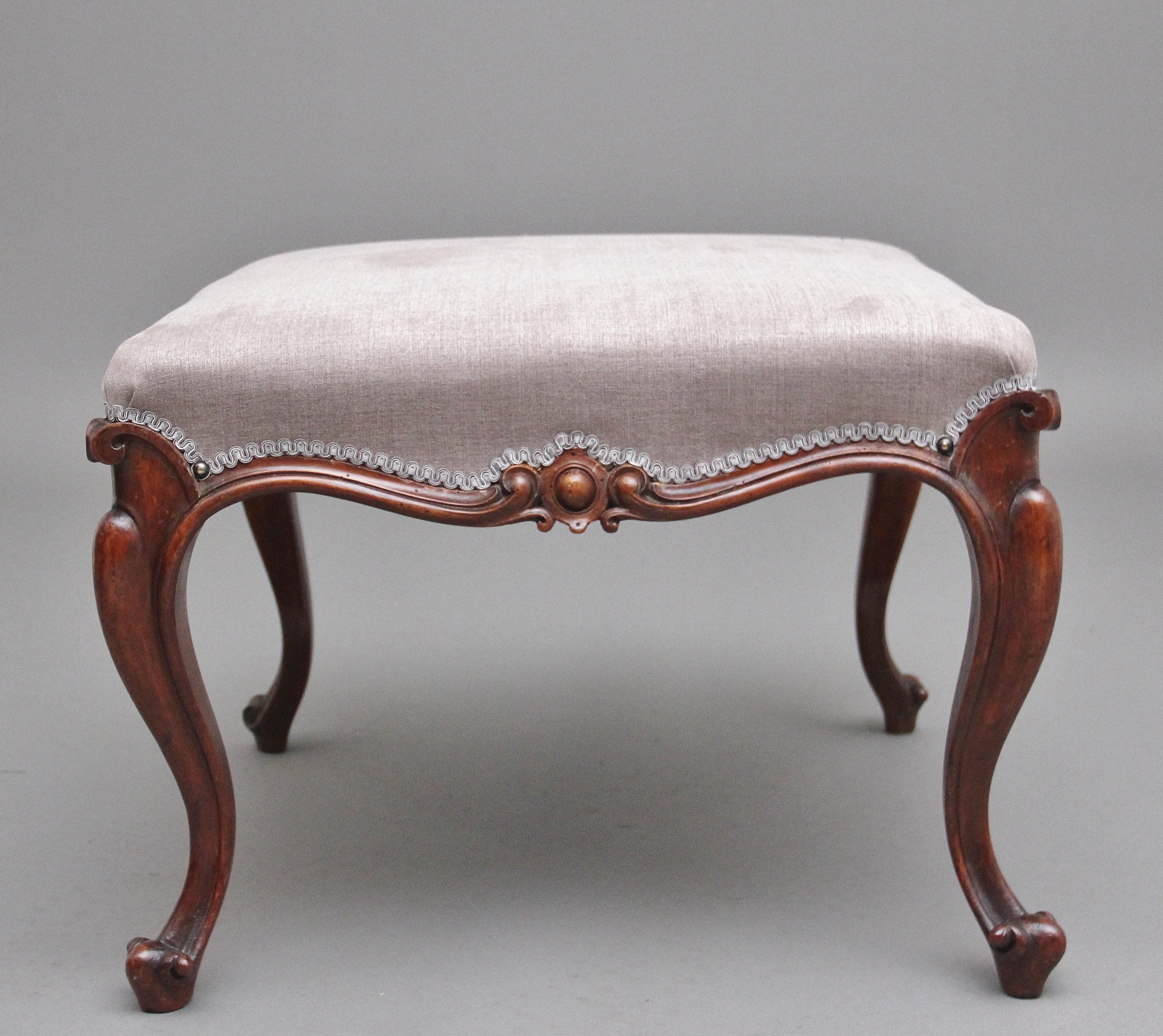 19th Century walnut stool having a recently reupholstered grey coloured stuff over seat finished with a decorative scroll trim, the foliate carved arched edge on cabriole legs. Circa 1860.