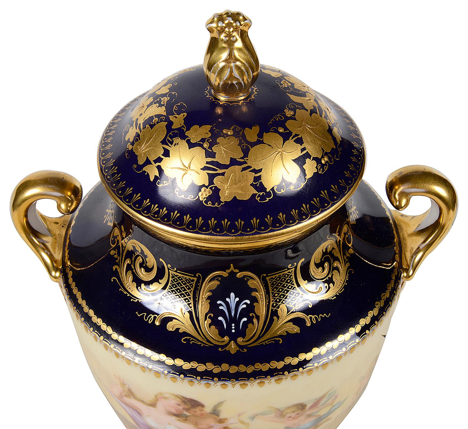 A fine quality late 19th Century Vienna porcelain lidded two handle vase, having a cobalt blue ground, gilded scrolling decoration, a cream coloured central band with a classical scene of a reclining maiden with cherubs playing. The vase standing on
