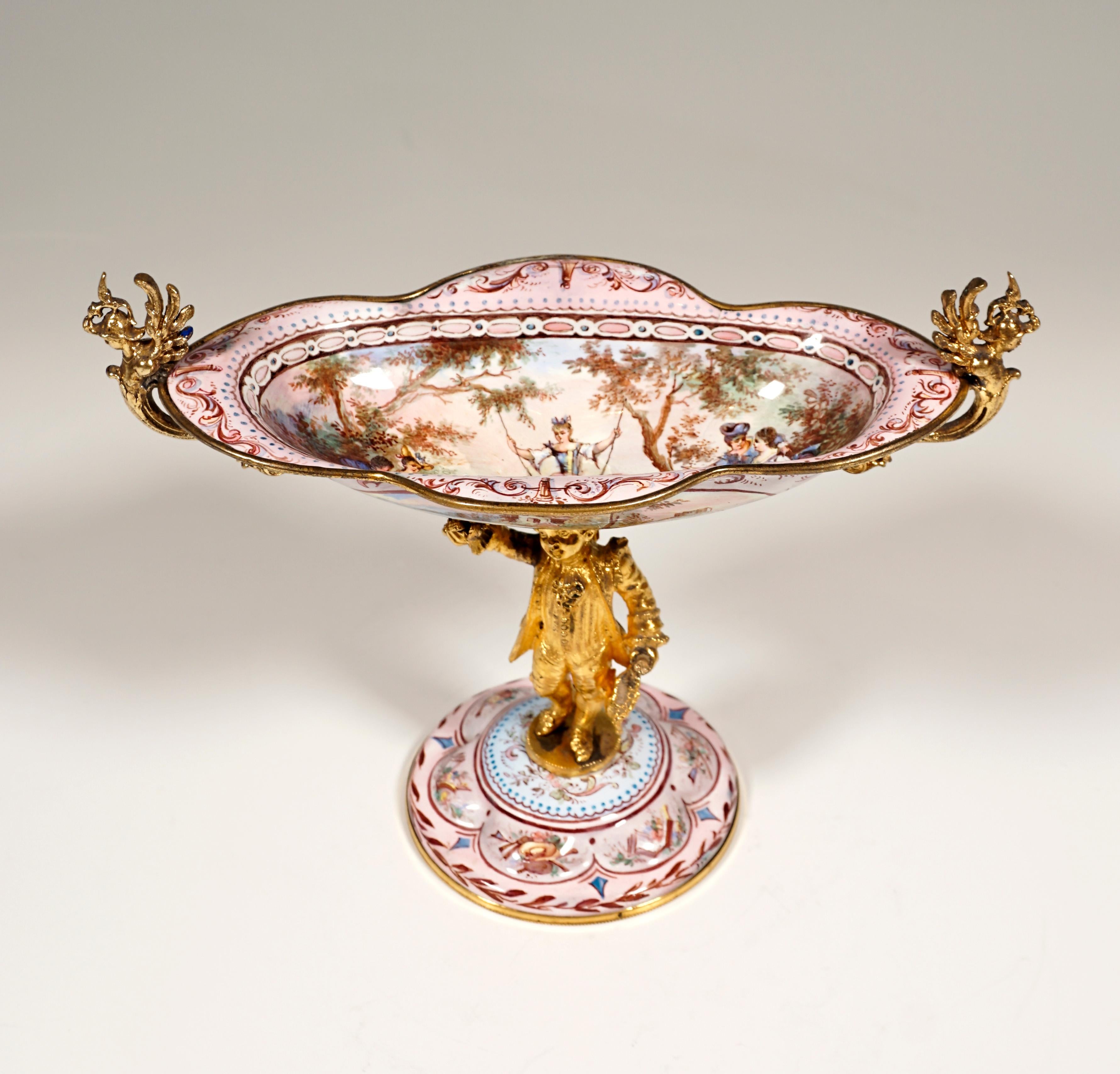 Finest Viennese Enamel Work from around 1880:
Fire-gilded bronze, elongated oval bowl and arched foot painted with colored enamel with Watteau scenes and richly detailed arabesque decoration, a three-dimensional, fire-gilded rococo boy with a wig