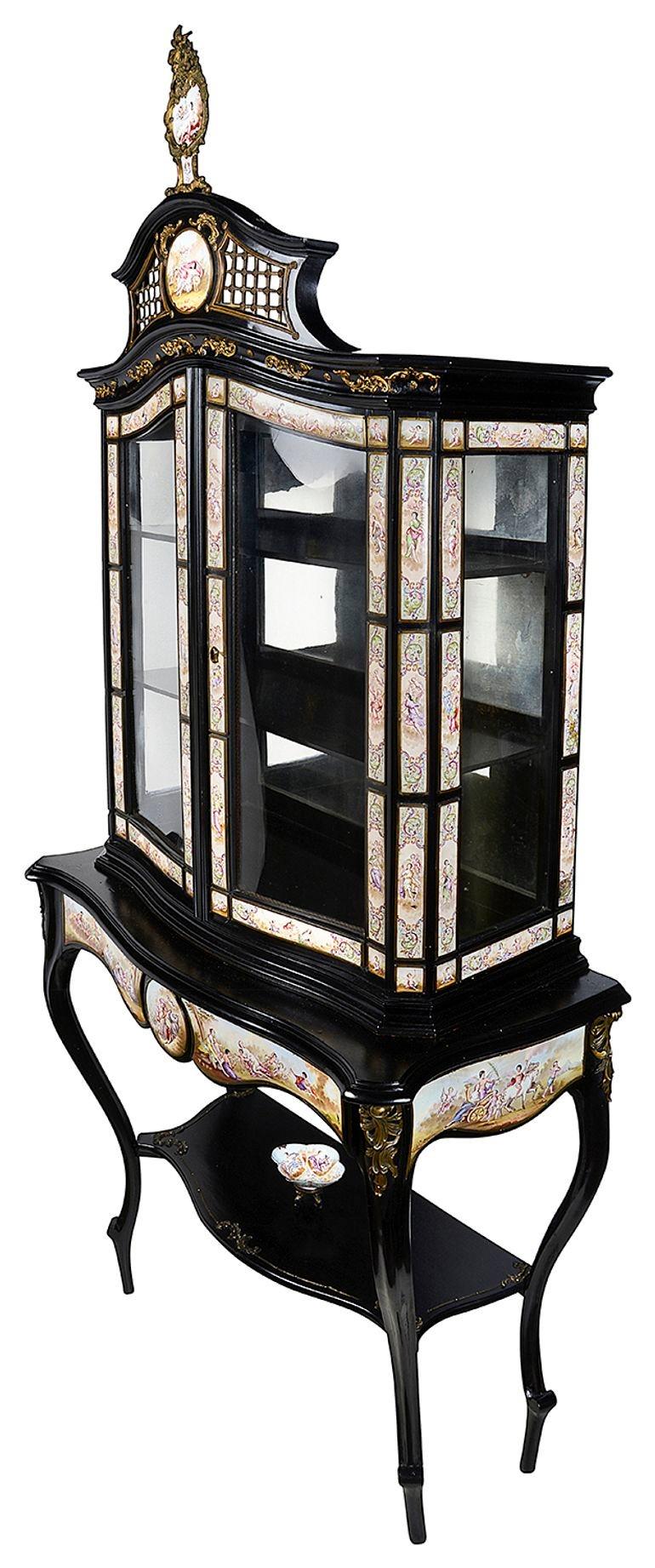 A rare latte 19th Century Austrian (Viennese) enamel decorated display cabinet. Having gilded ormolu mounts and pierced trellis to the cornice, a mirror backed, glazed cabinet above, with enamel plaques depicted romantic and classical scenes. Two