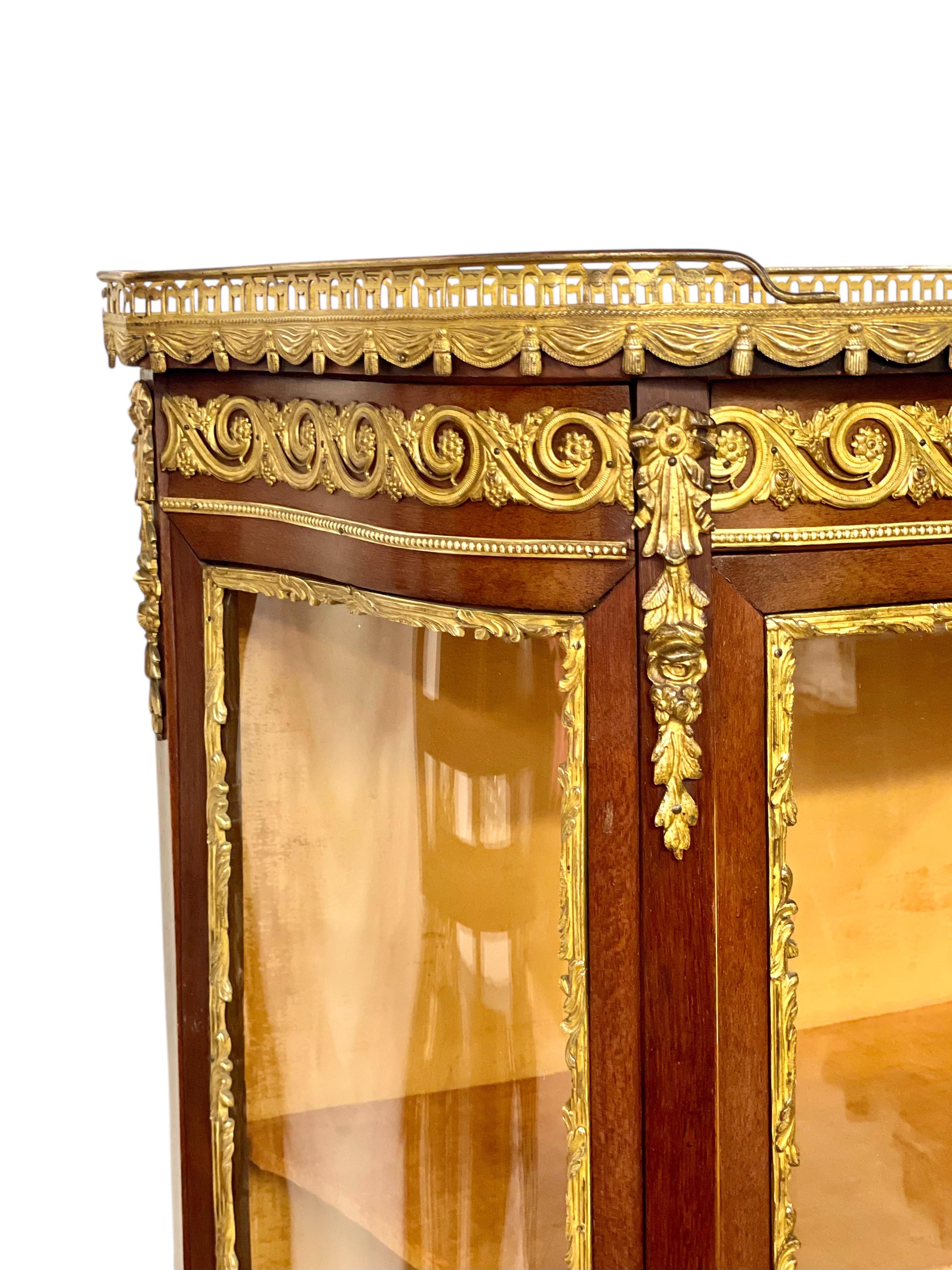 Esta exquisita vitrina francesa del siglo XIX es un notable ejemplo del estilo de transición entre Luis XV y Luis XVI, que mezcla las graciosas curvas del periodo rococó con la elegancia clásica del neoclasicismo. Fabricada en nogal fino, presenta