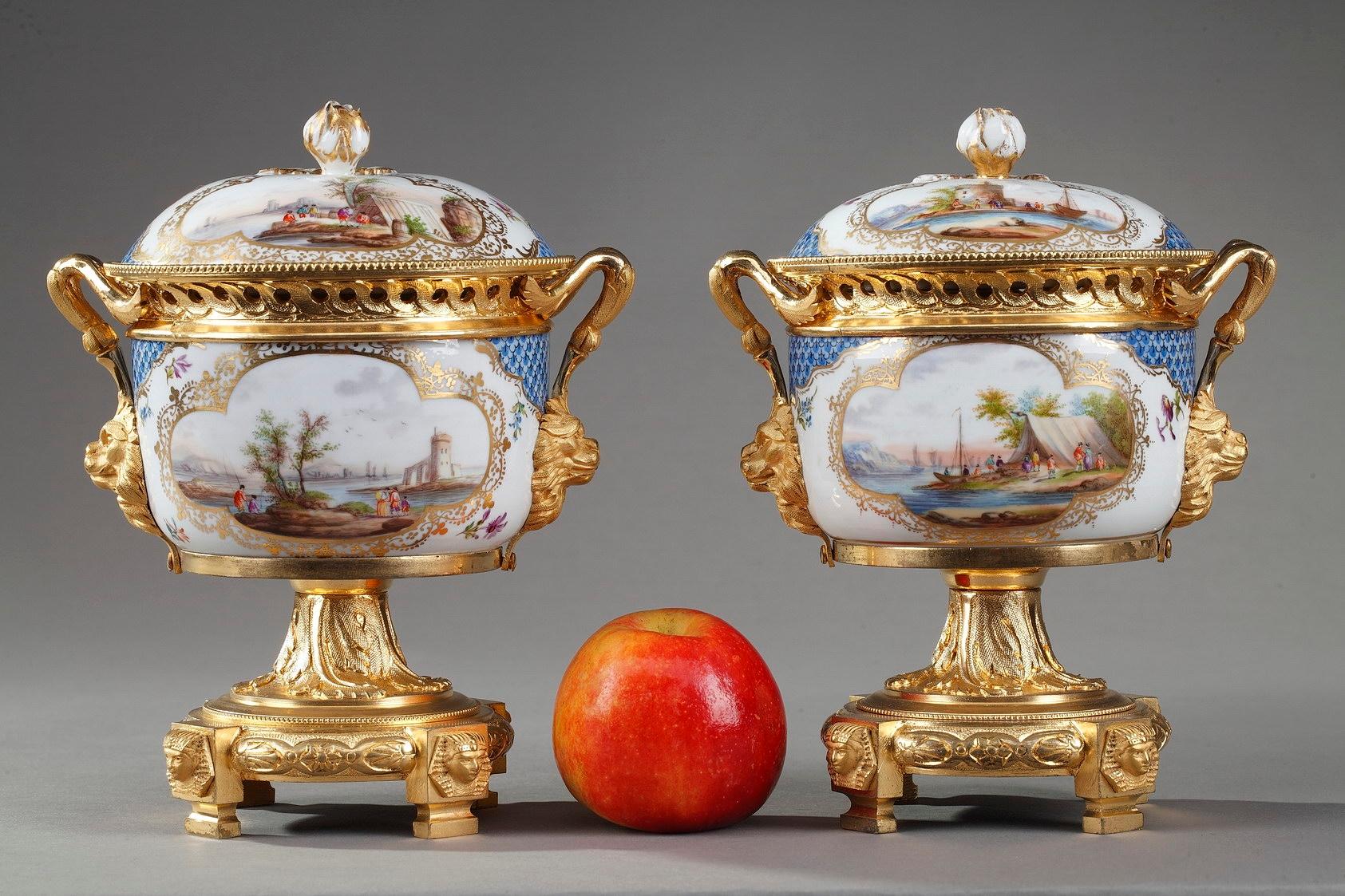 Pair of porcelain centerpiece vases for aromatic potpourri. Each vase displays port scenes in medallions highlighted with gold on white and blue background. The paunch and lid are decorated with delicately worked scales and flowers. Gilt bronze
