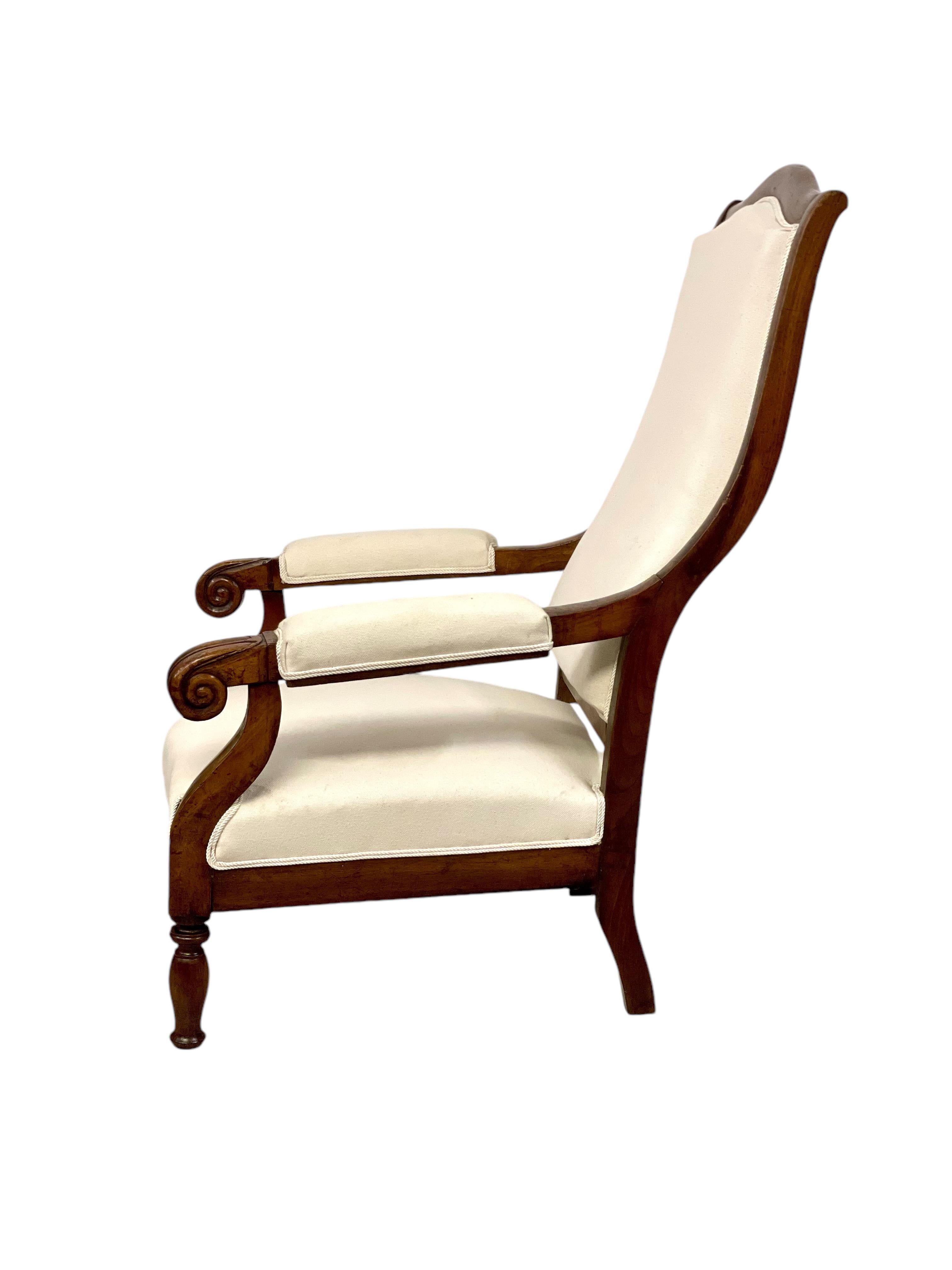 Questa elegante poltrona Voltaire presenta una struttura in noce massiccio, splendidamente intagliata con dettagli classici. Lo schienale alto e dolcemente curvo e la seduta imbottita offrono un comfort eccezionale, mentre il rivestimento beige