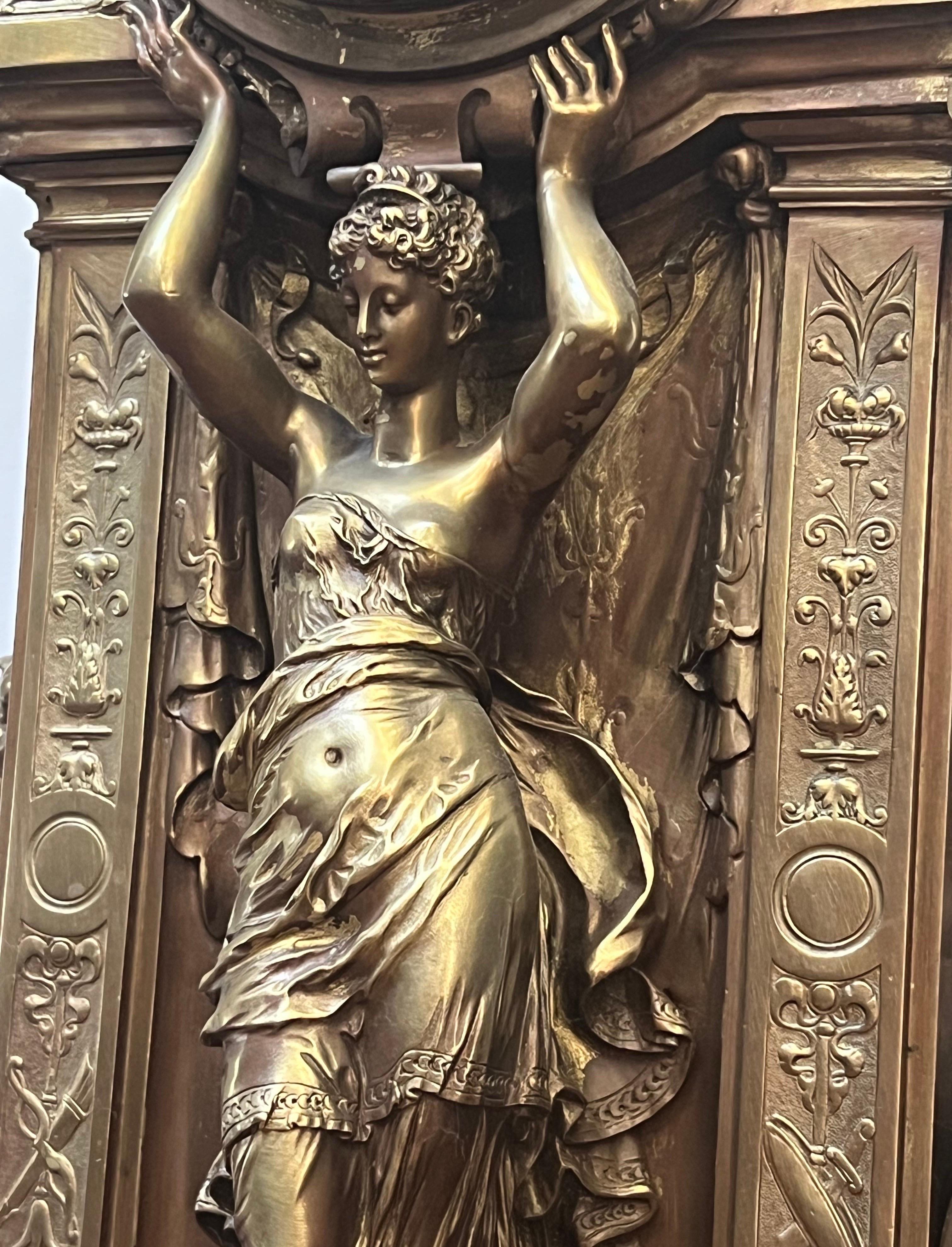 This beautiful 19th Century clock has exquisite attention to detail.  Cherubs are back to back at the top bell tower while a draped women holds the clock above her head.  