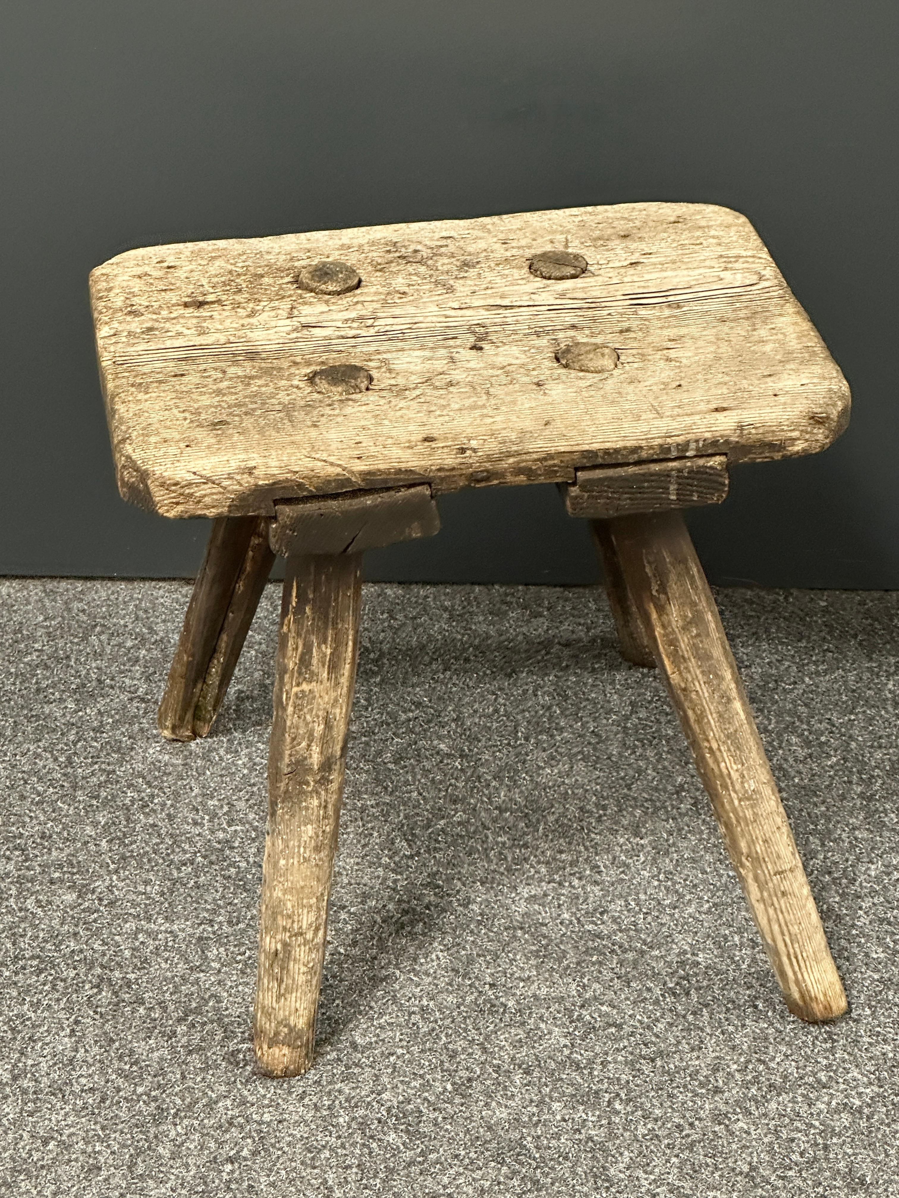 This 219th century wabi sabi 4 leg milking stool from Germany is an excellent example of this style. The piece has a square, rustic-looking seat made of wooden planks and is supported by four spindle legs. The stool has a simple, understated design