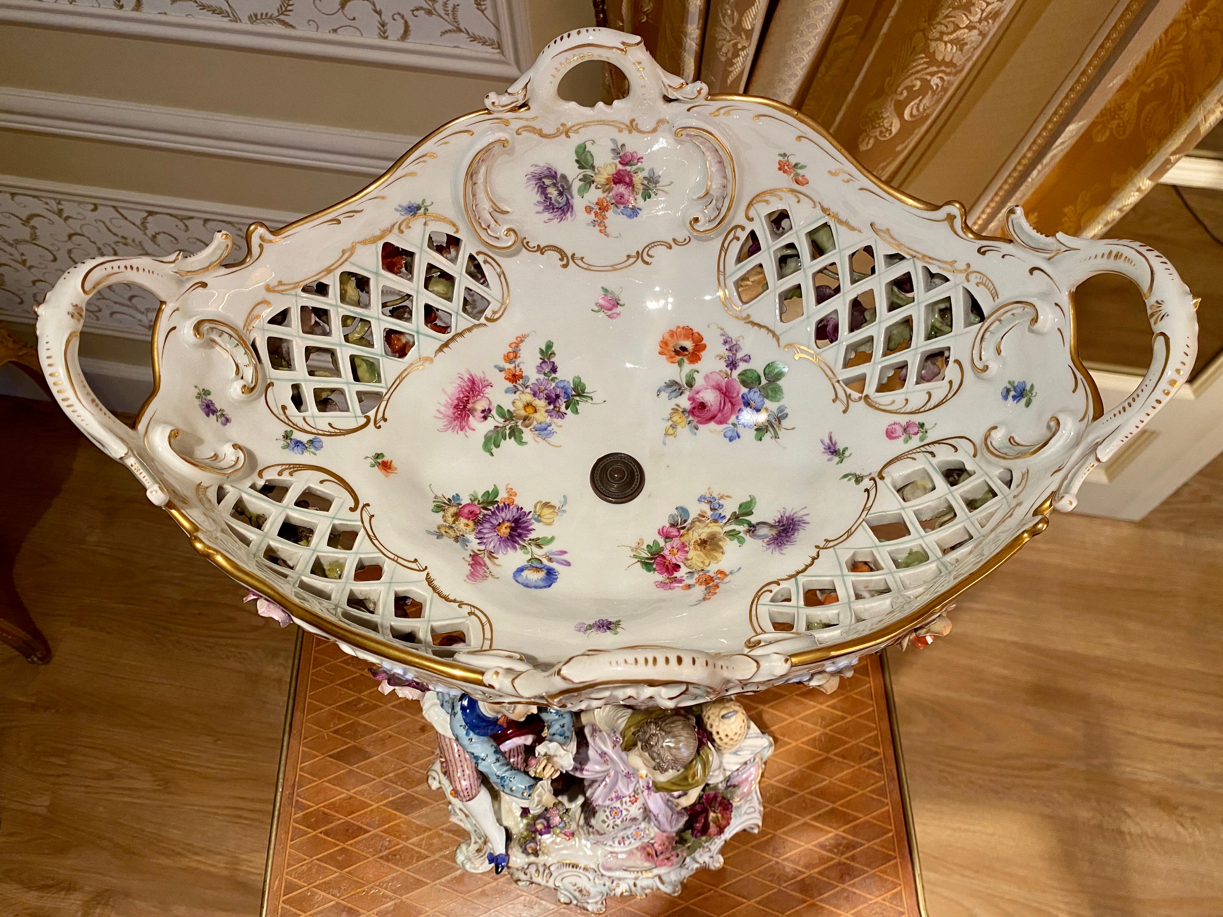 Superb and large centerpiece in German porcelain. Base representing a gallant scene composed of three characters, the set surmounted by a large openwork cup with floral decorations. This piece is in very good condition, has a stamp underneath and a