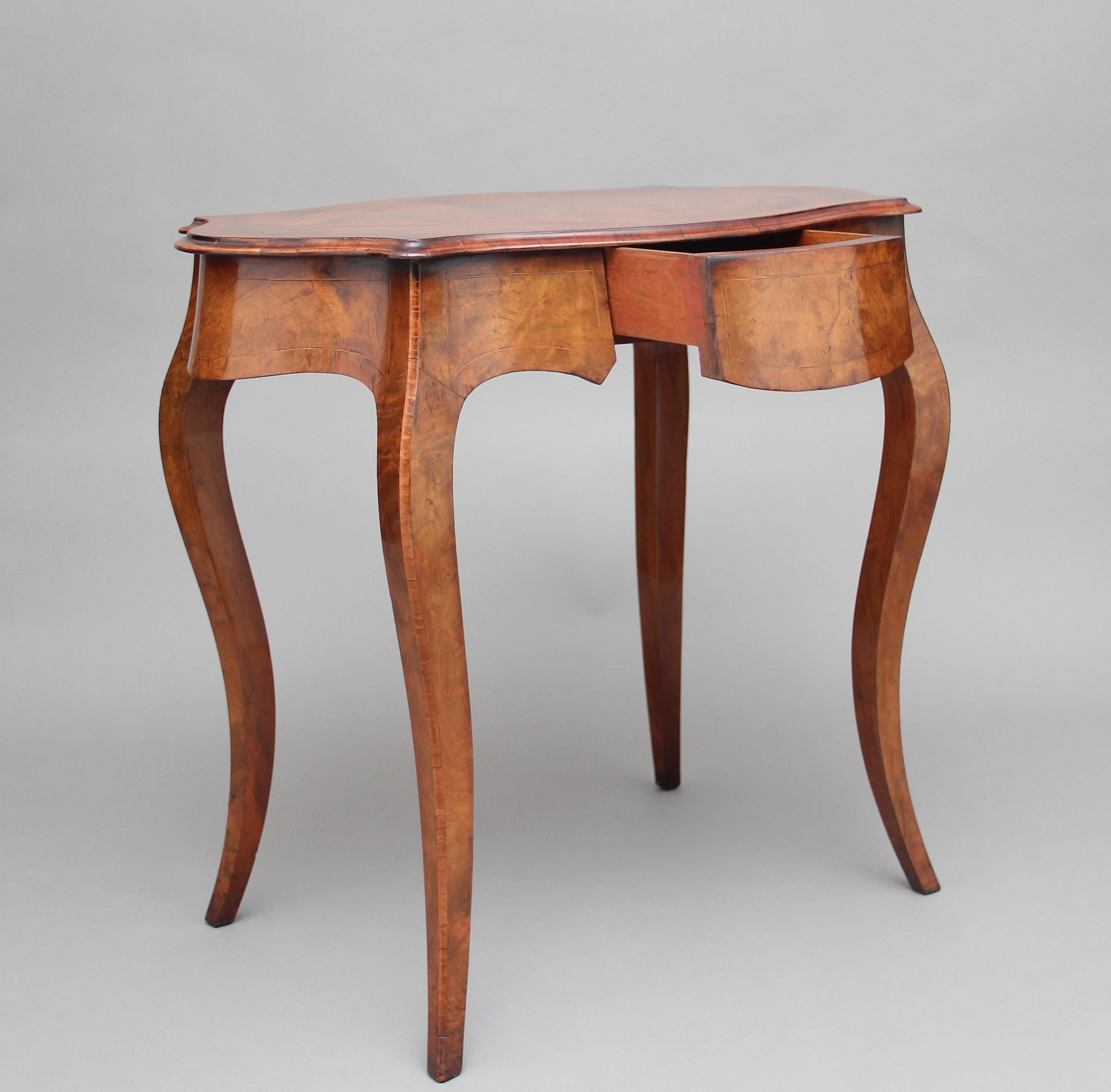 19th century walnut and boxwood line centre or occasional table of serpentine form, the moulded edge, quarter veneered, crossbanded shaped top having a lovely inlaid pattern at the centre, with a mahogany lined frieze drawer below, shaped apron,