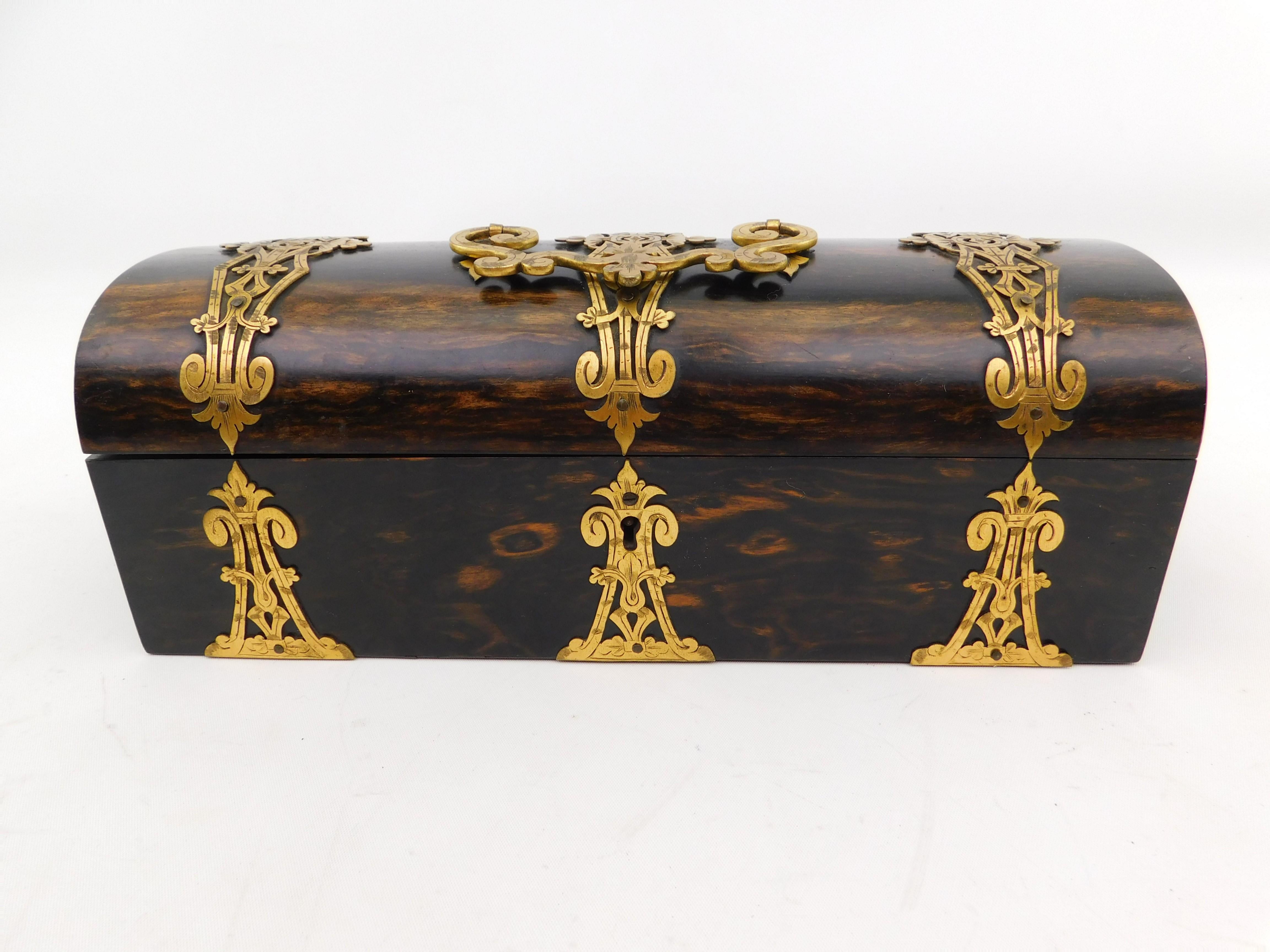 English walnut and brass dome-top box with Mother-of-Pearl, ca. 1860. With 6 sewing tools, 4 have mother of pearl handles, 7 pieces of circular fabric samples that were in the box. Plaque inscribed Trussell 16 & 17 St. Brighton. Has a lock but no