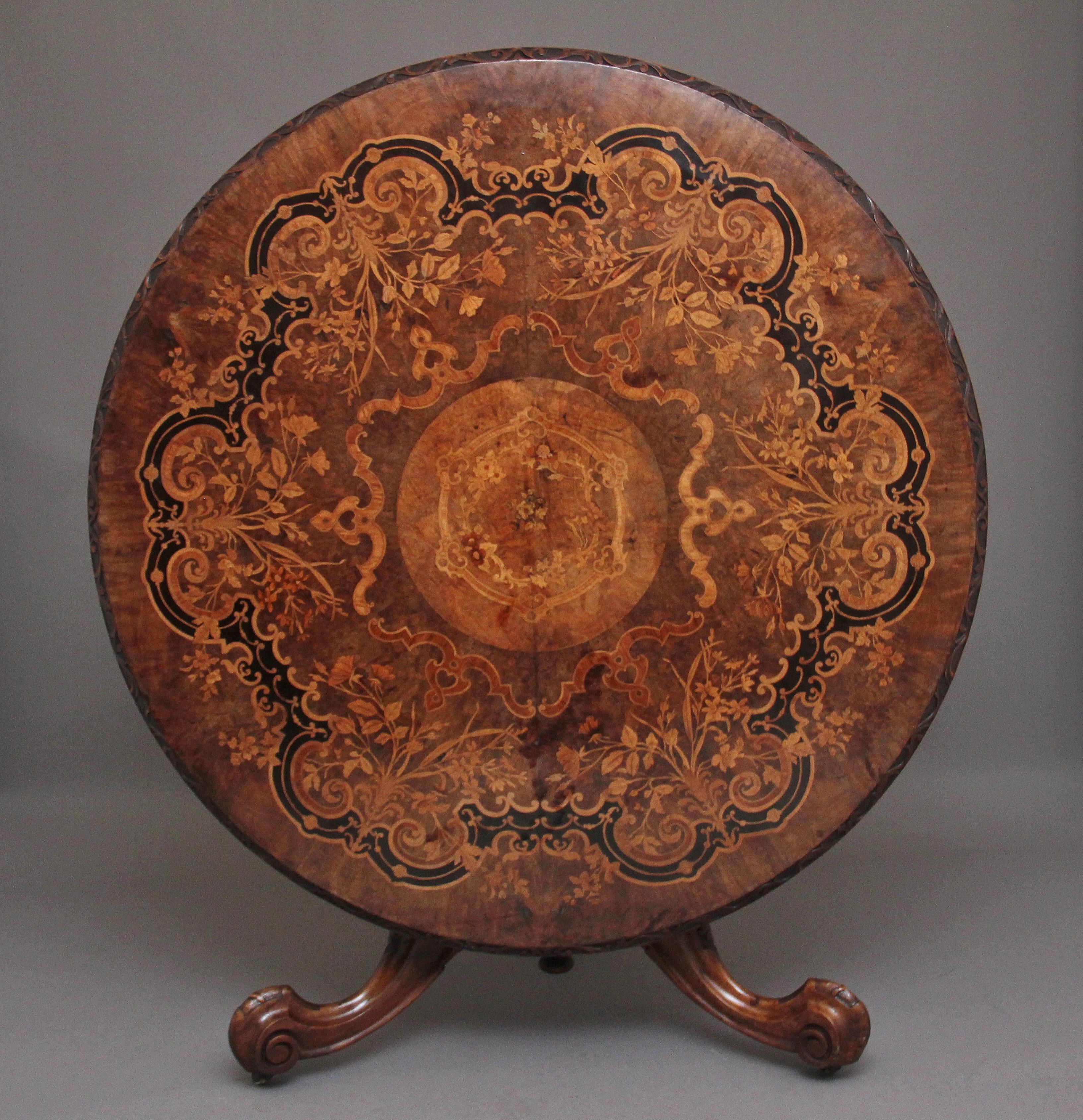 An exhibition quality 19th century walnut and marquetry centre / breakfast table, the circular top having a decorative foliate carved edge, profusely inlaid with exotic specimen timbers with flowers and foliage and fabulously inlaid at the centre,