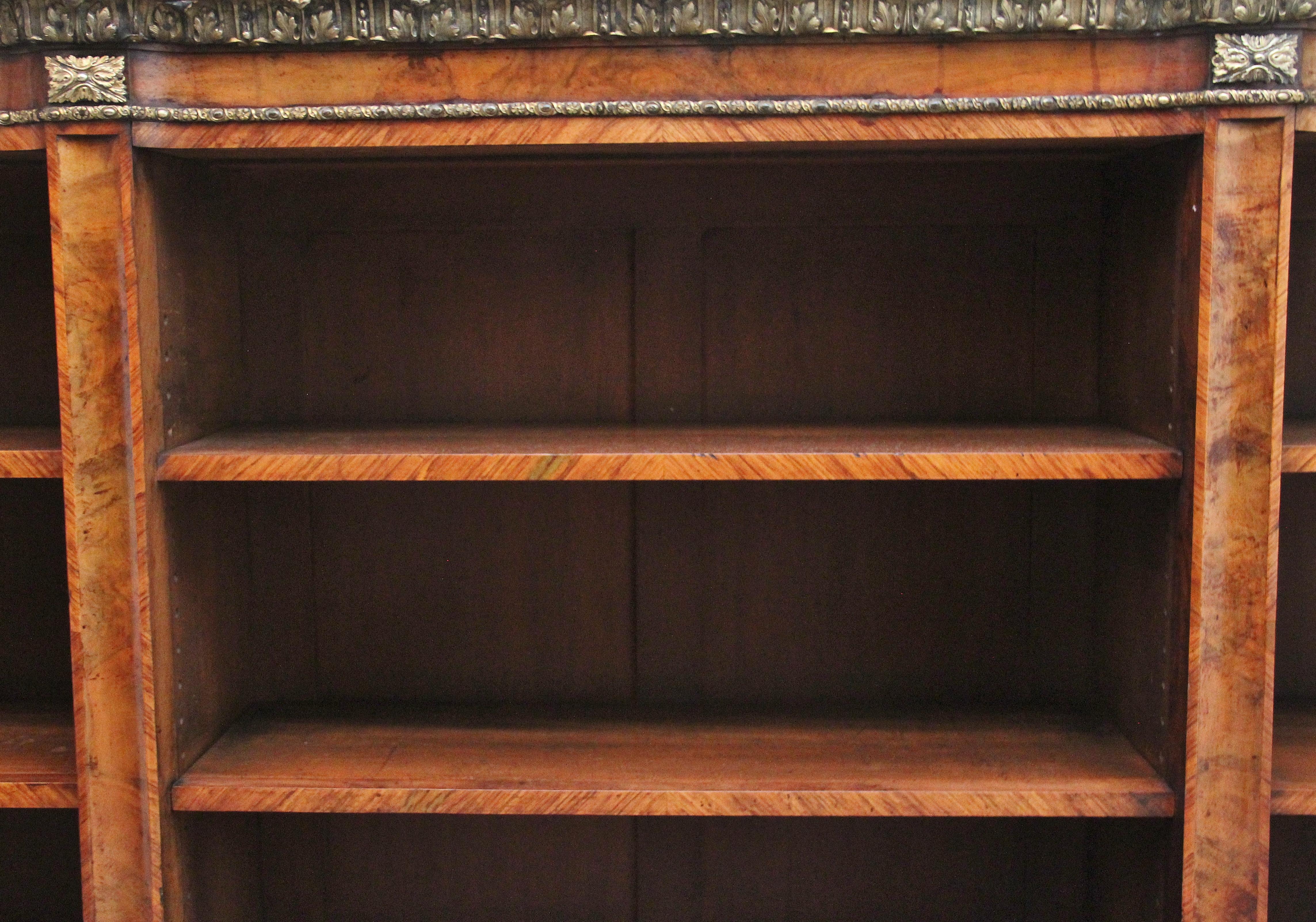 An exhibition quality large 19th Century walnut and ormolu open bookcase, having a wonderful figured and shaped top which is also crossbanded, the frieze below having decorative engraved ormolu moulding and further ormolu moulding at the bottom of