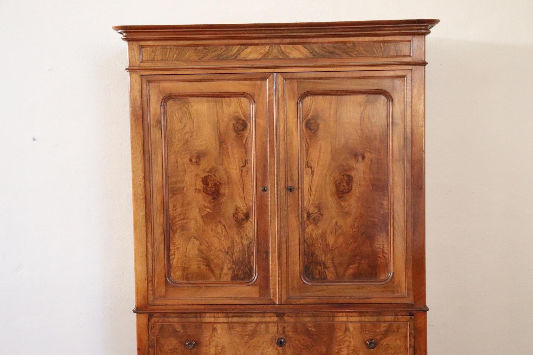 Elegant antique wardrobe in precious walnut wood 1850s. In the upper part two doors with three shelves inside. The first of the three large drawers becomes a practical support surface for writing with small drawers inside and two secret compartments