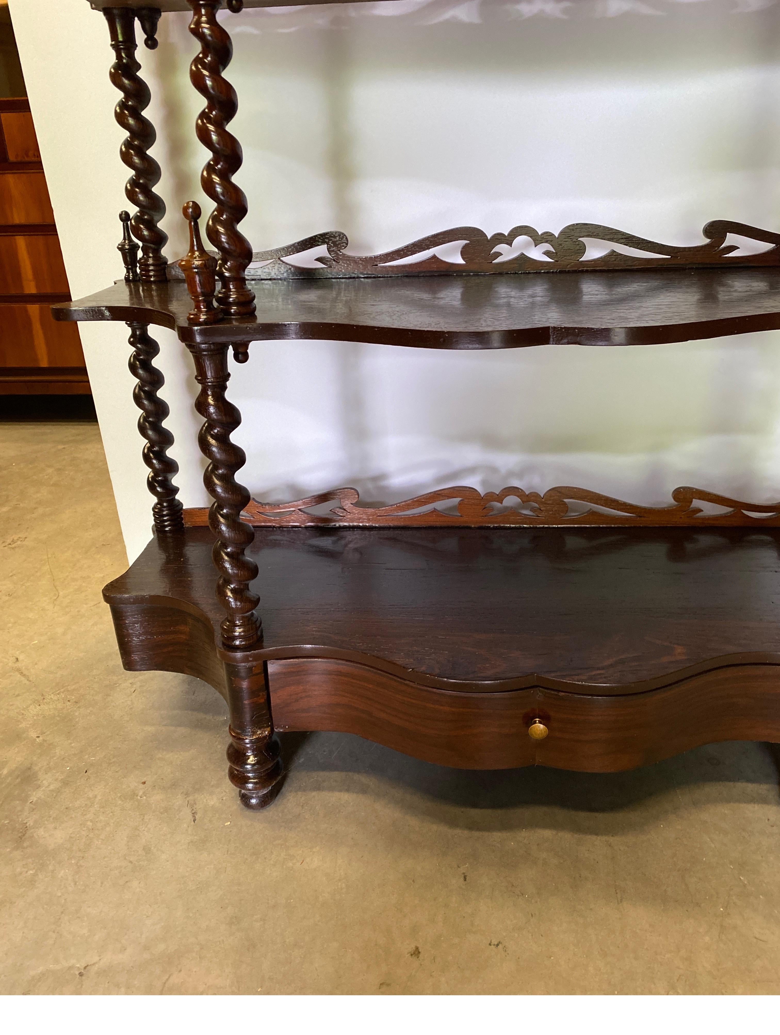Handsome dark walnut barley twist open book case. The six shelves of variegated sizes with a functional brawer at the bottom. The supports are hand carved barley twist design with finals at the top. The brace at the back of the shelves with pierced